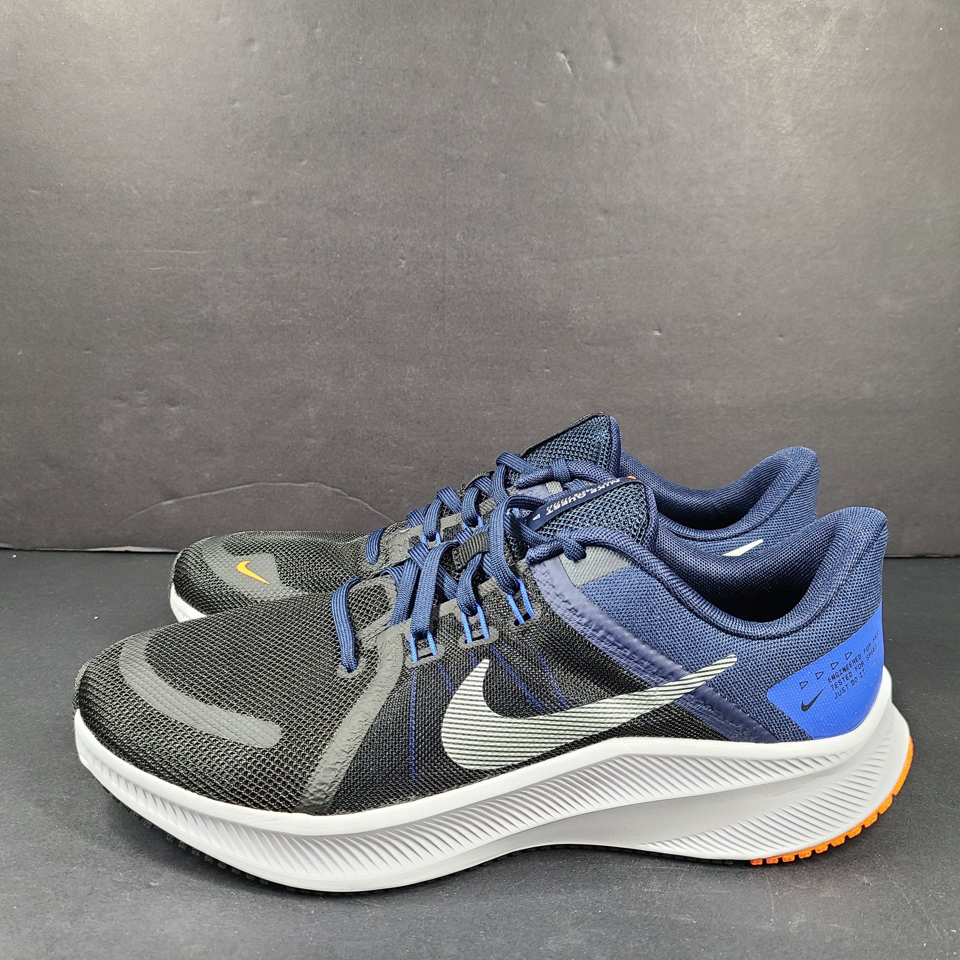 Black, blue and orange Nike Quest 4 running shoes in US size 9 with breathable mesh upper and cushioned sole.