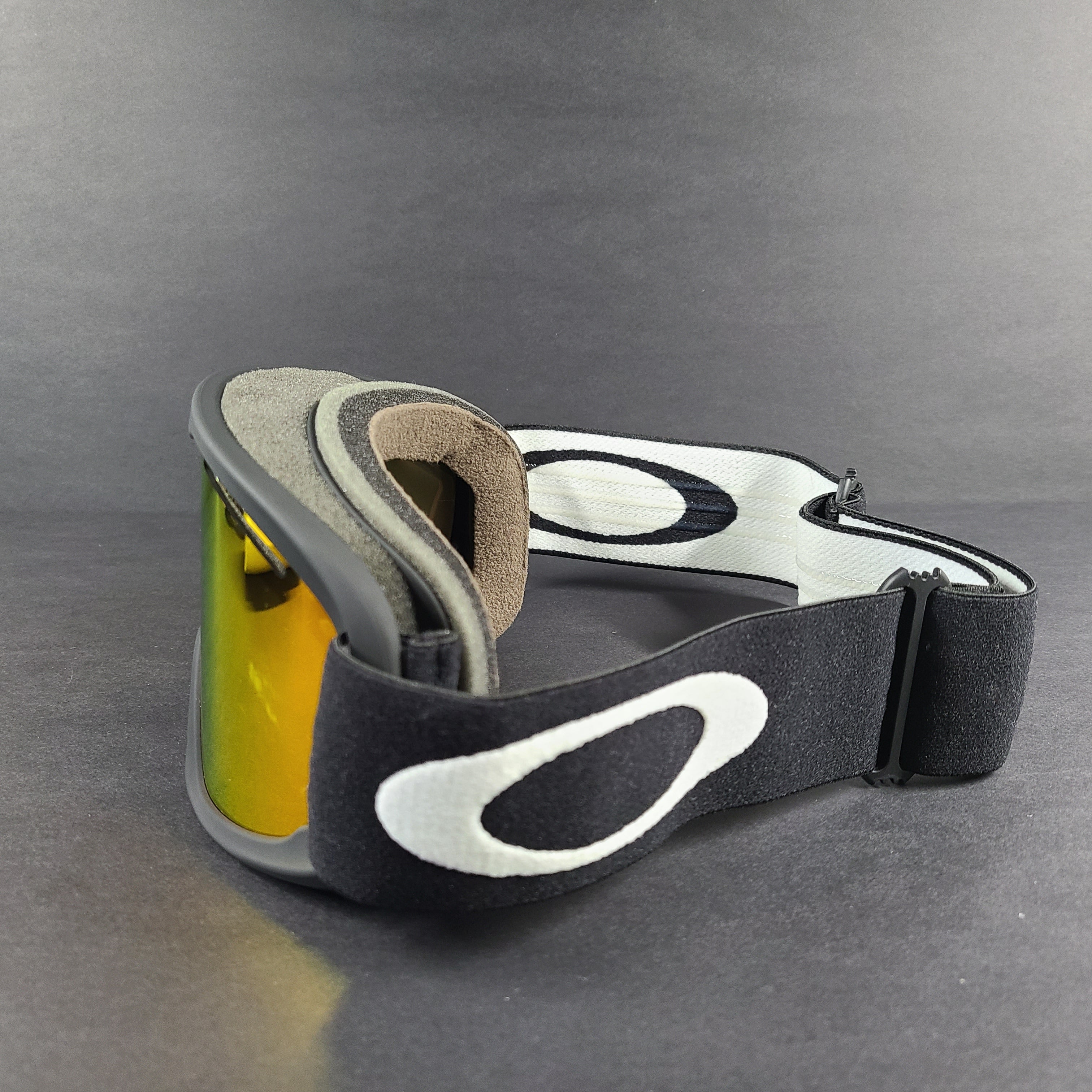 Oakley black snow goggles feature an orange lens and include an extra replacement lens and storage bag.