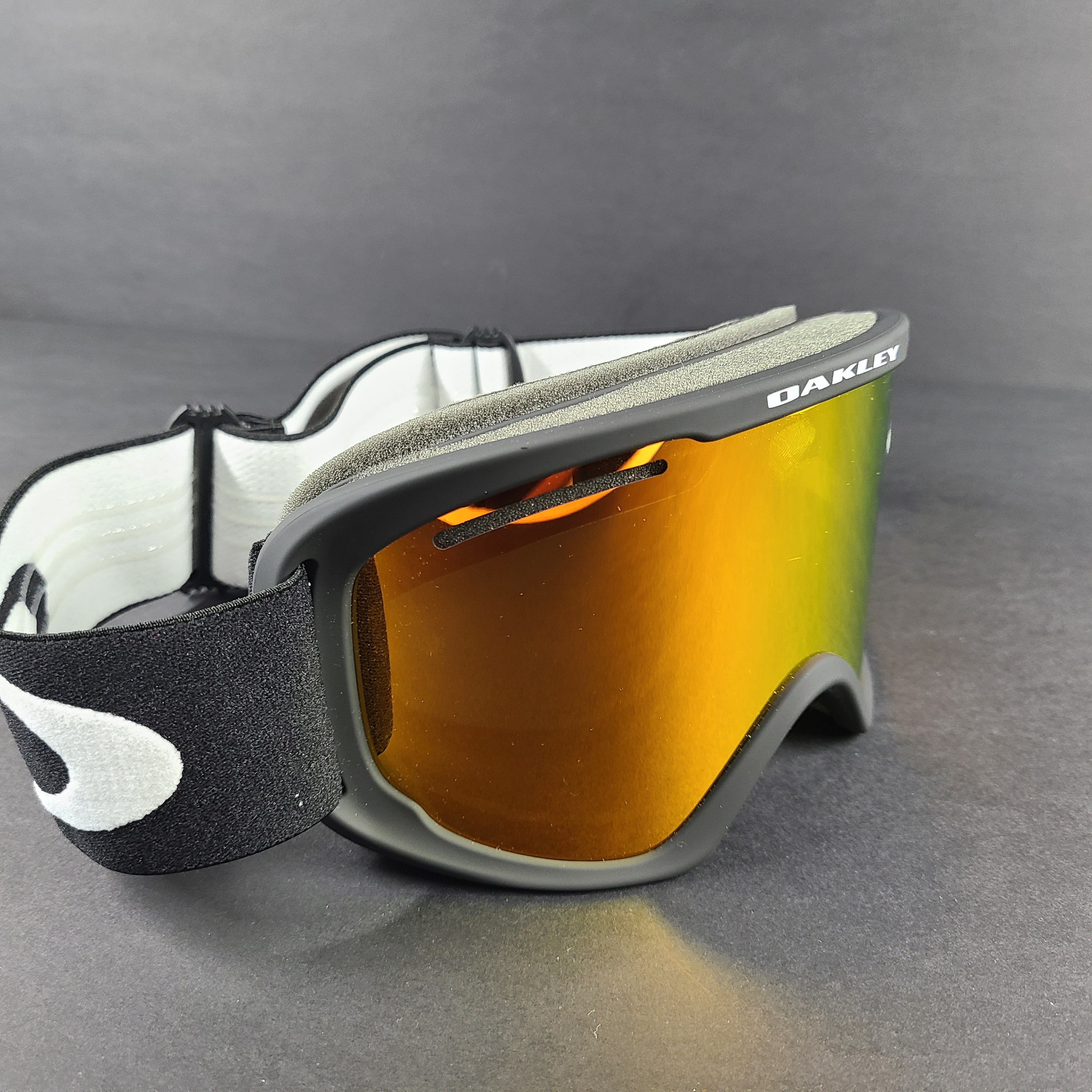 Oakley black snow goggles feature an orange lens and include an extra replacement lens and storage bag.