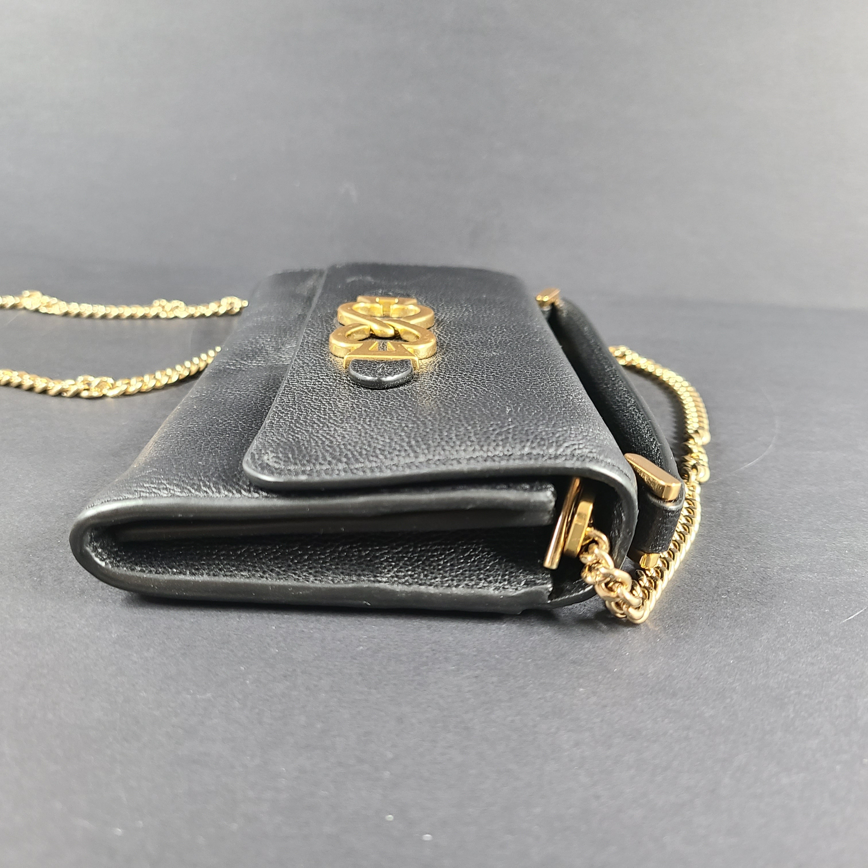 Black Kate Spade leather crossbody handbag with gold chain strap and branded logo.