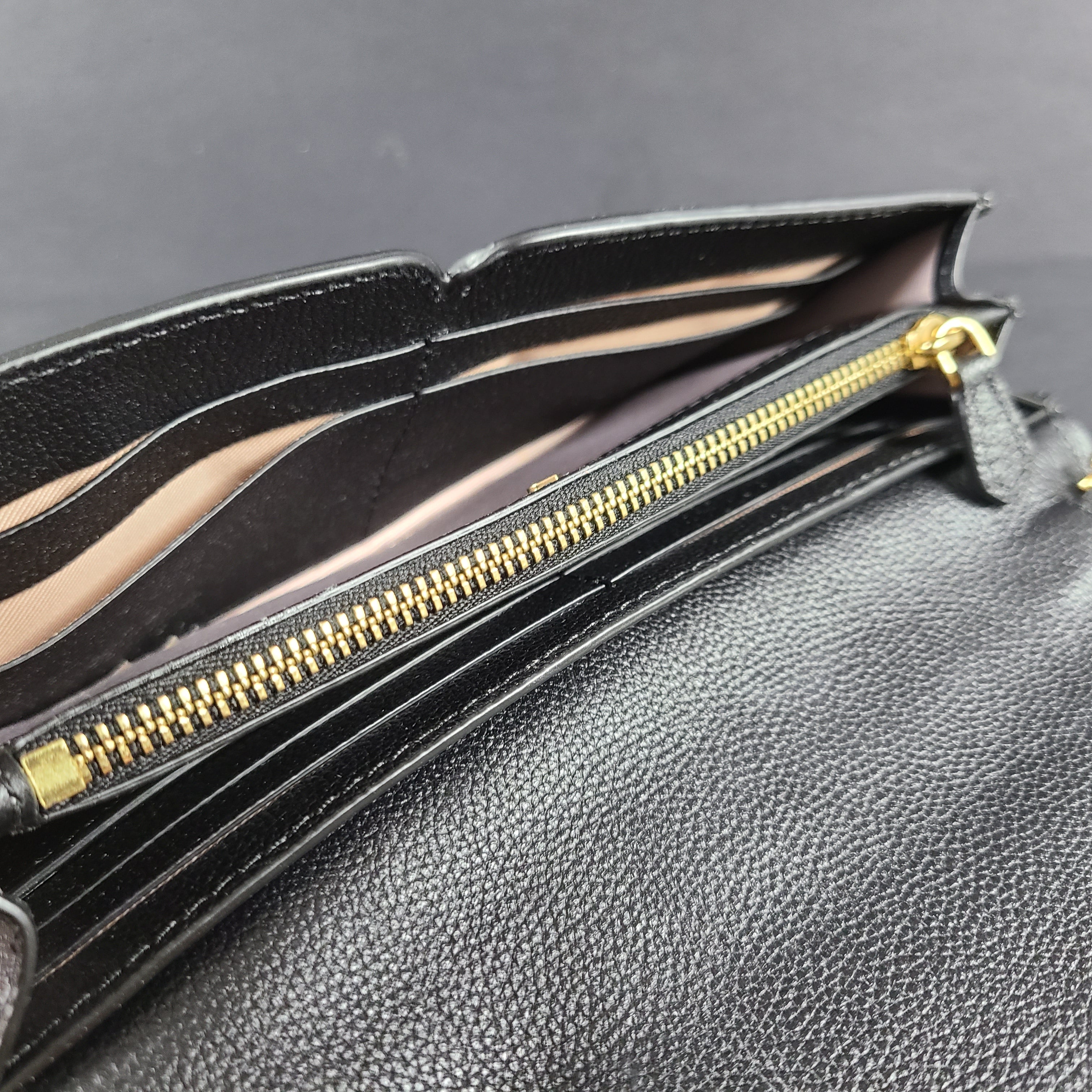 Black Kate Spade leather crossbody handbag with gold chain strap and branded logo.