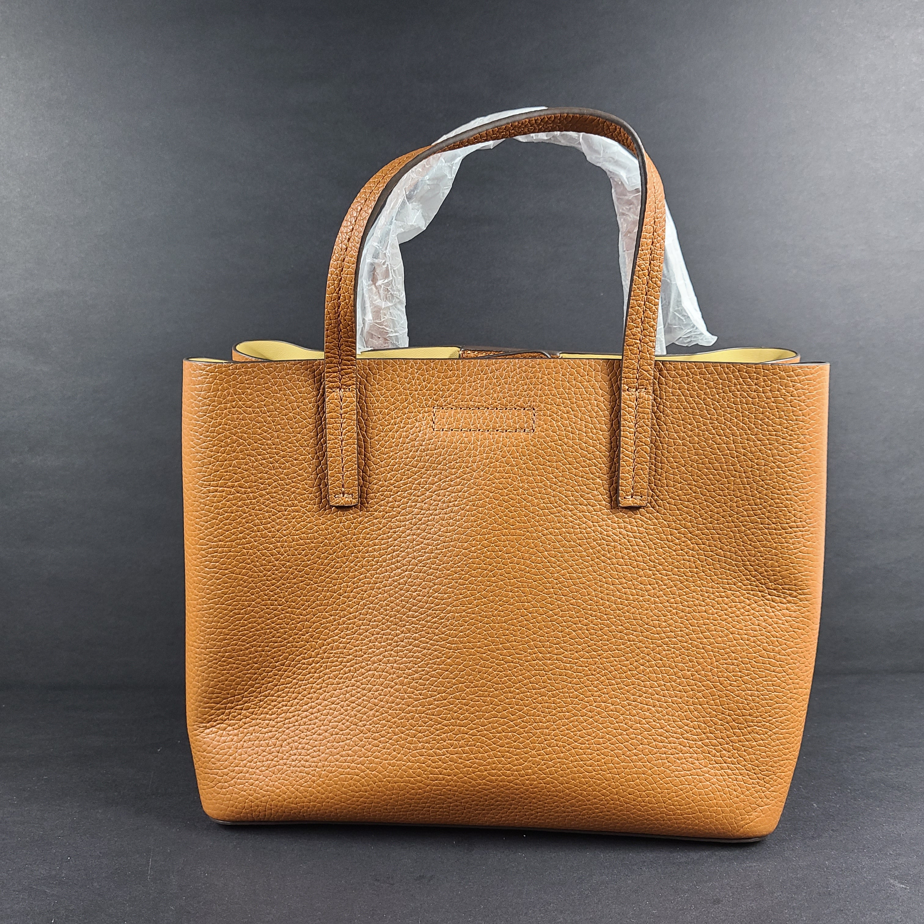Tory Burch brown leather handbag with a detachable shoulder strap and protective-wrapped handles.