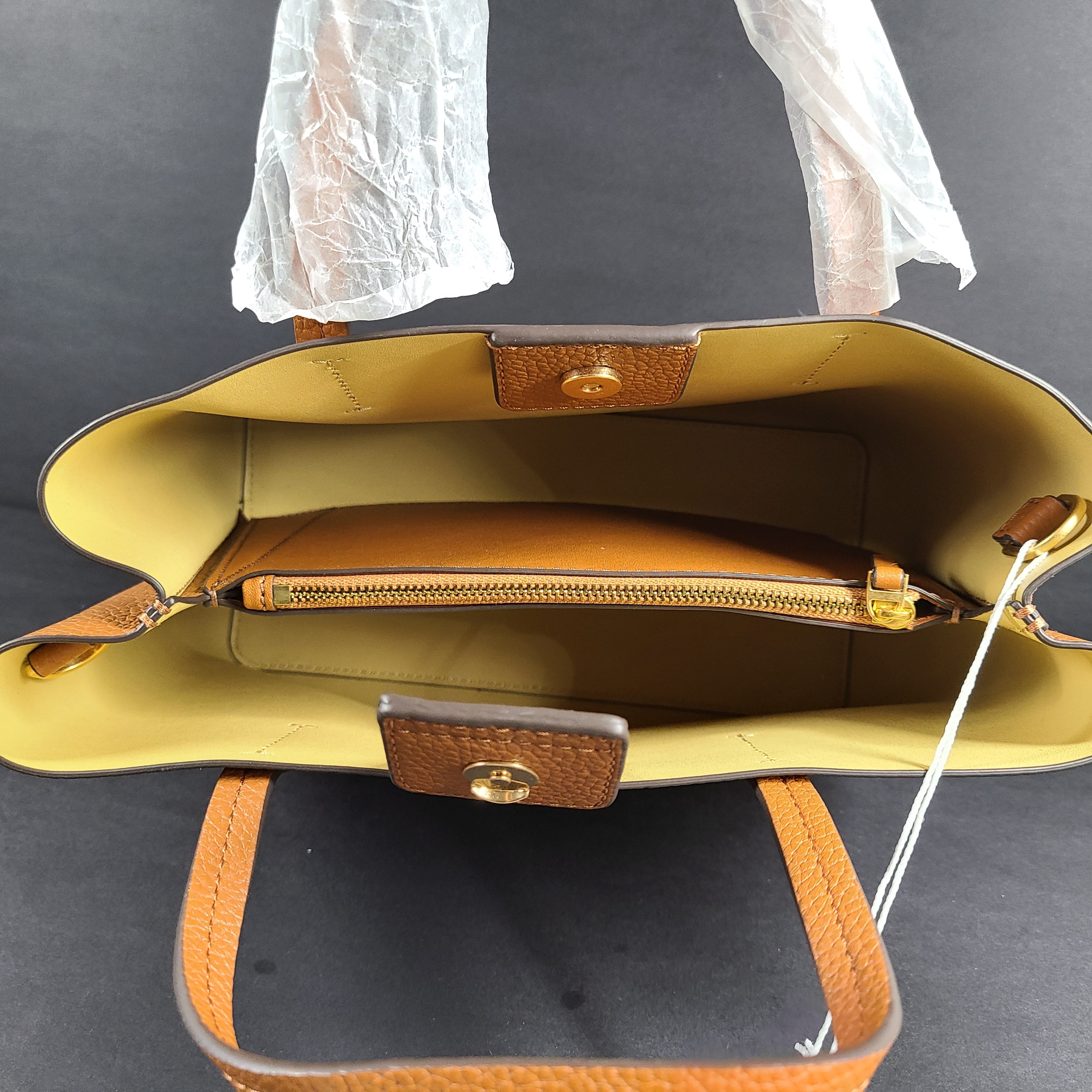 Tory Burch brown leather handbag with a detachable shoulder strap and protective-wrapped handles.