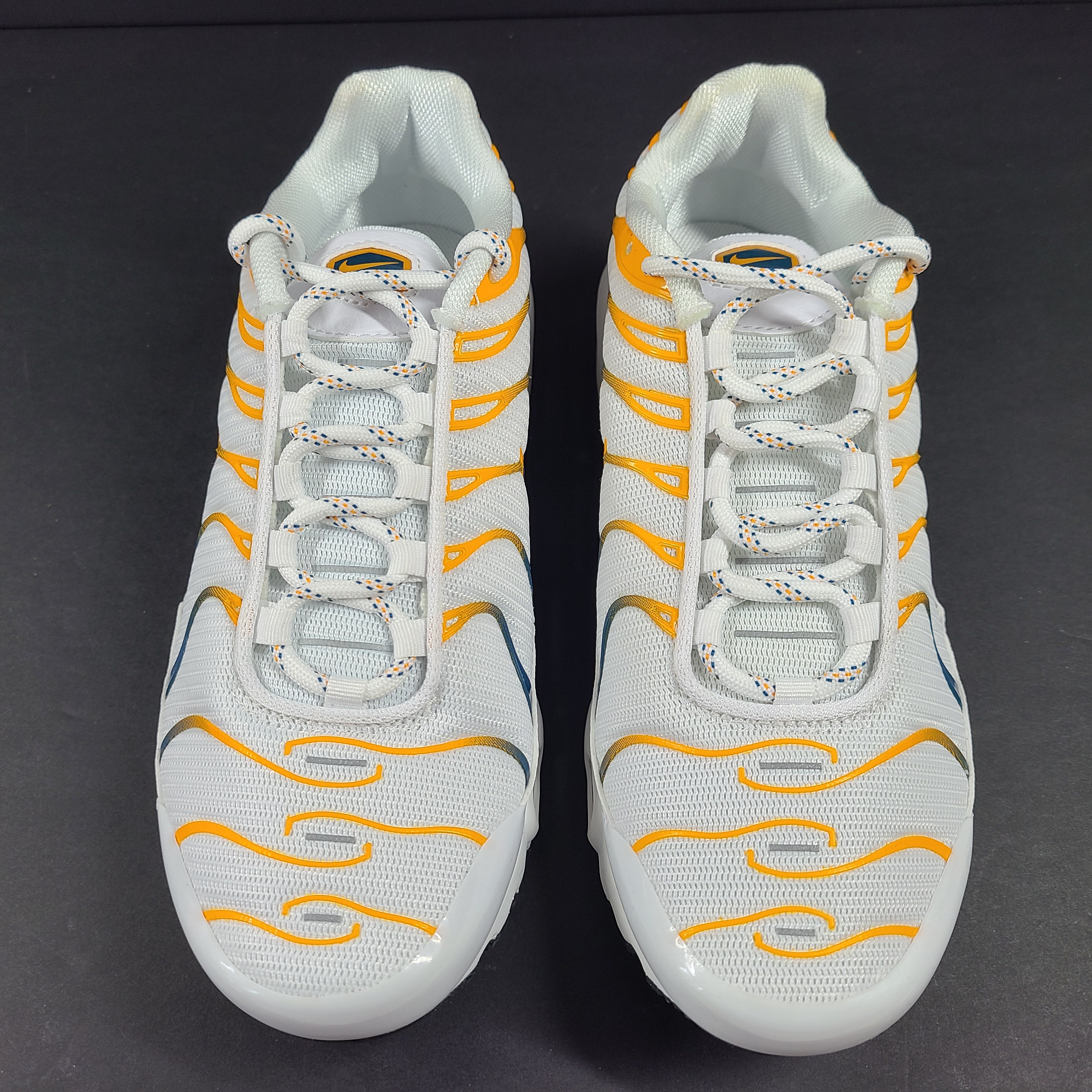 Nike Air Max Plus in white, orange and blue with signature Air cushioning and a youth fit for active wear.