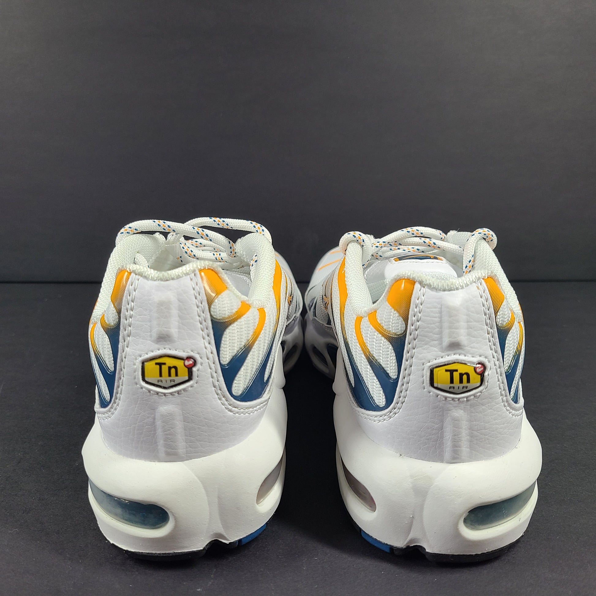 Nike Air Max Plus in white, orange and blue with signature Air cushioning and a youth fit for active wear.