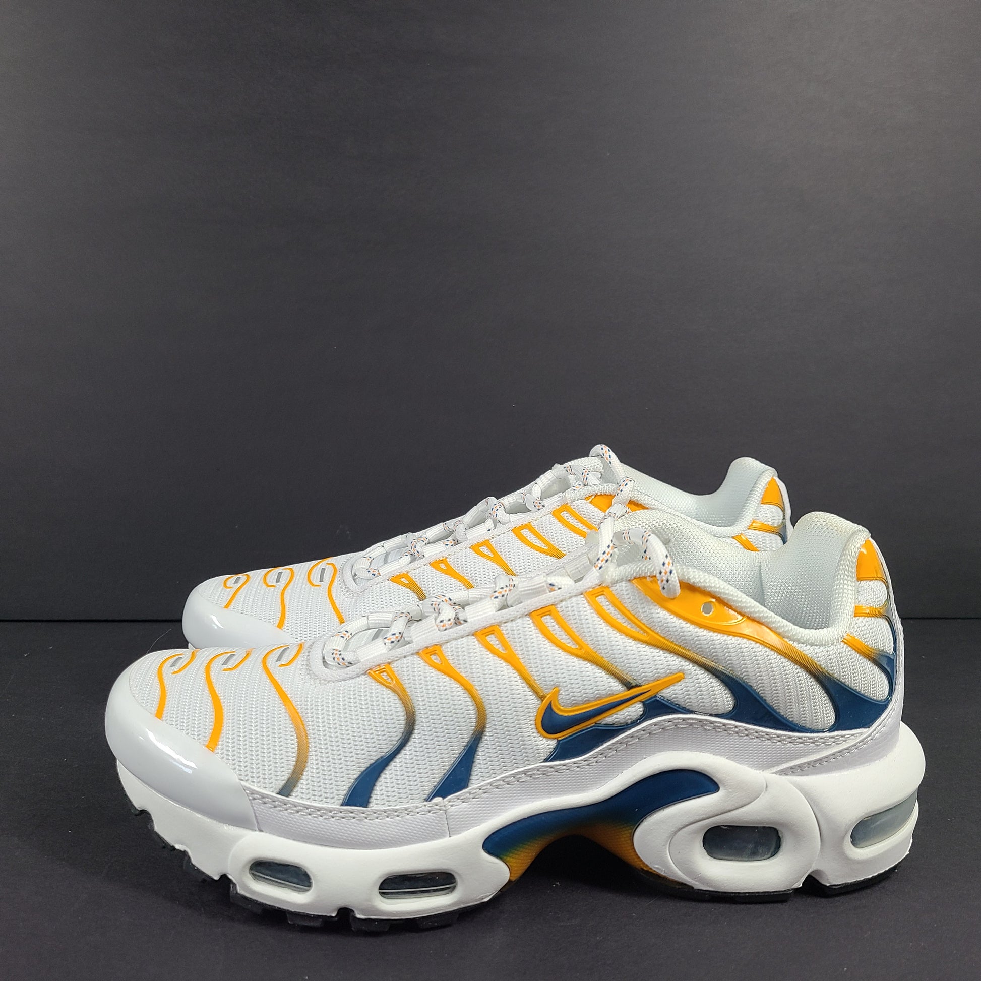 Nike Air Max Plus in white, orange and blue with signature Air cushioning and a youth fit for active wear.