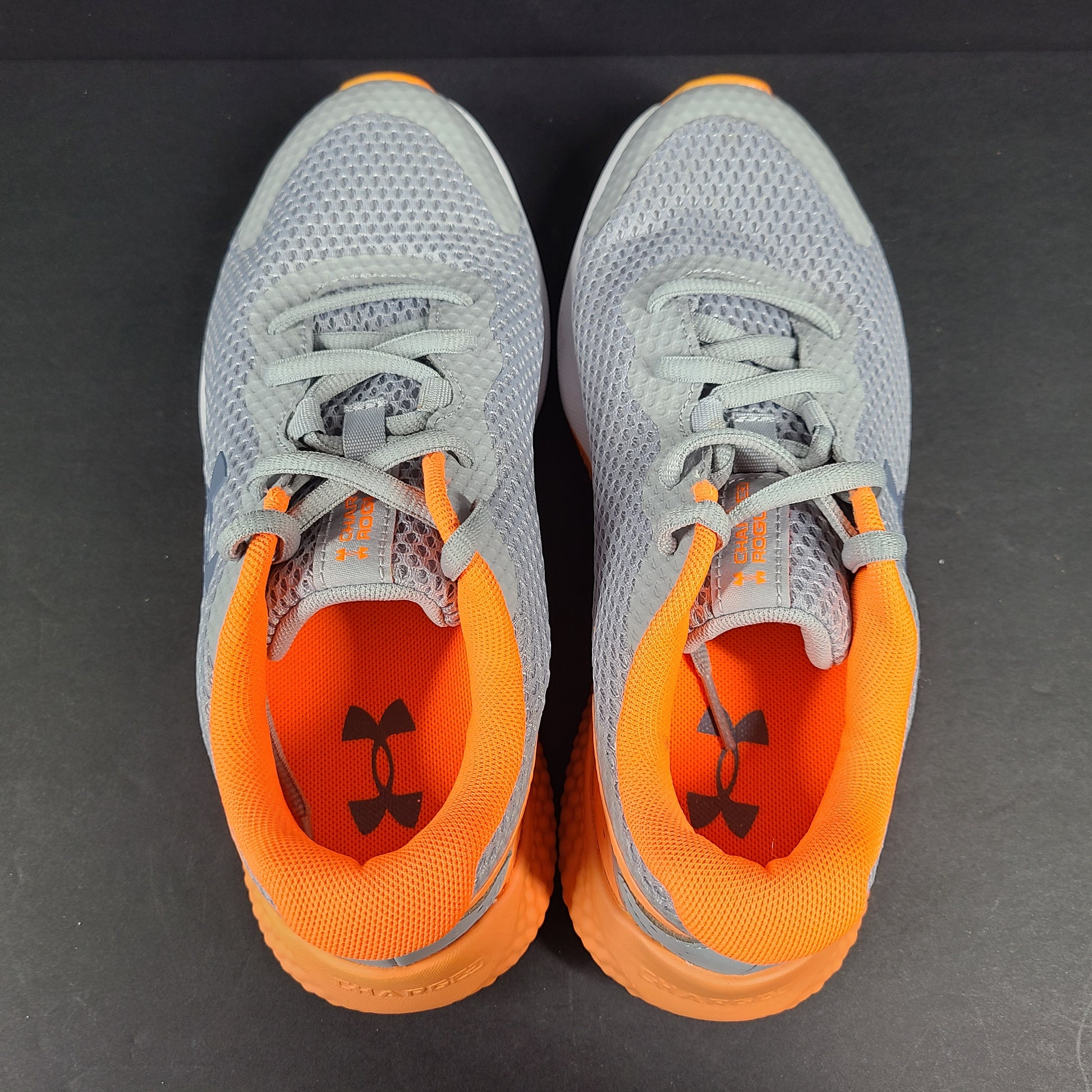 Under Armour Charged Rogue youth running shoes in gray with orange accents and a low-profile silhouette.