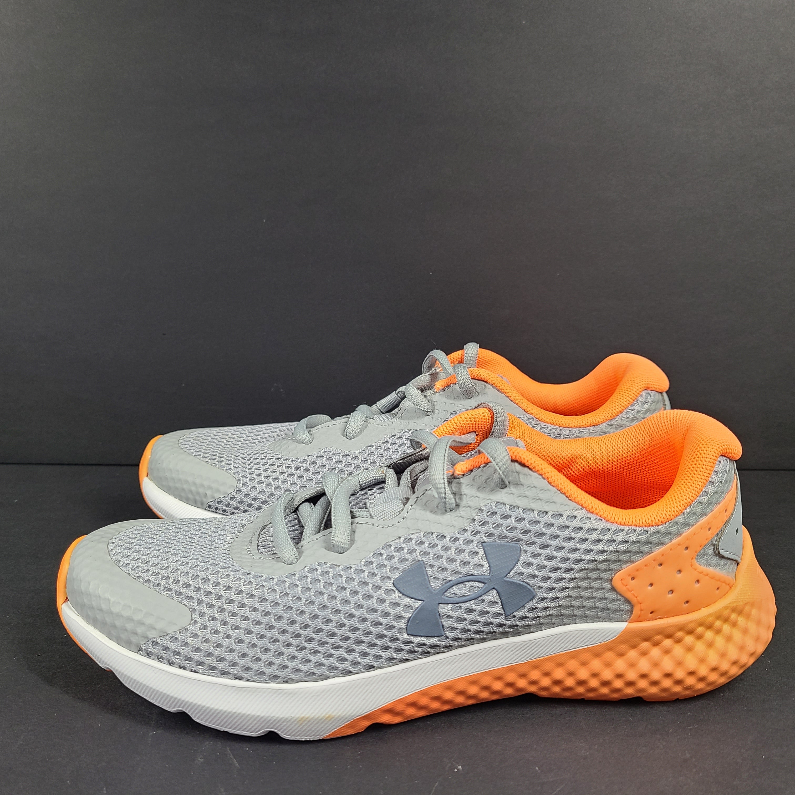 Under Armour Charged Rogue youth running shoes in gray with orange accents and a low-profile silhouette.