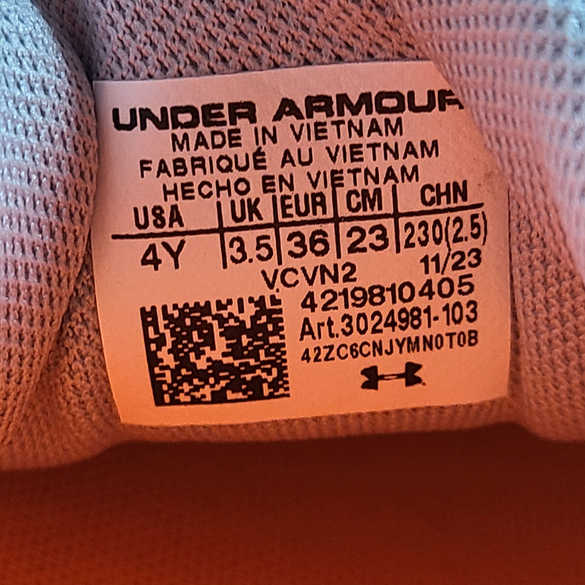 Under Armour Charged Rogue youth running shoes in gray with orange accents and a low-profile silhouette.
