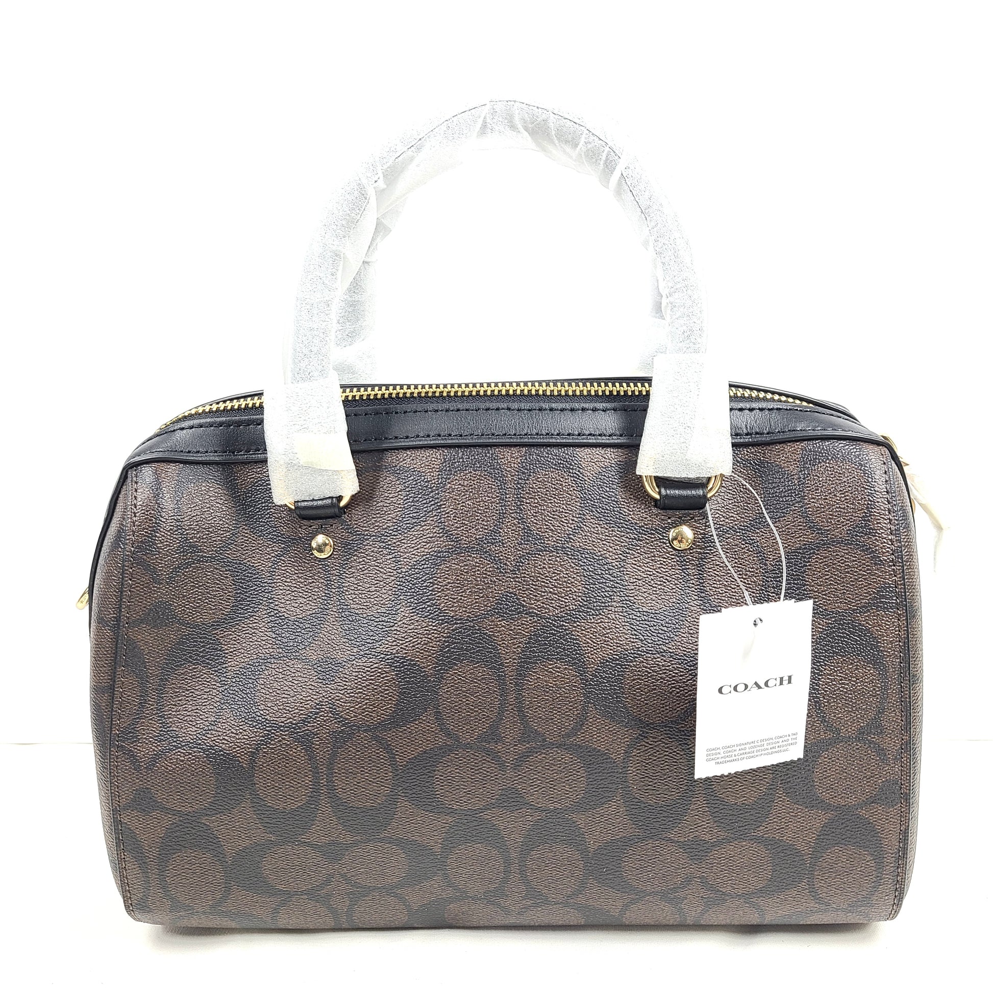 Coach brown signature-print handbag with black accents, including an interior label with the model number.
