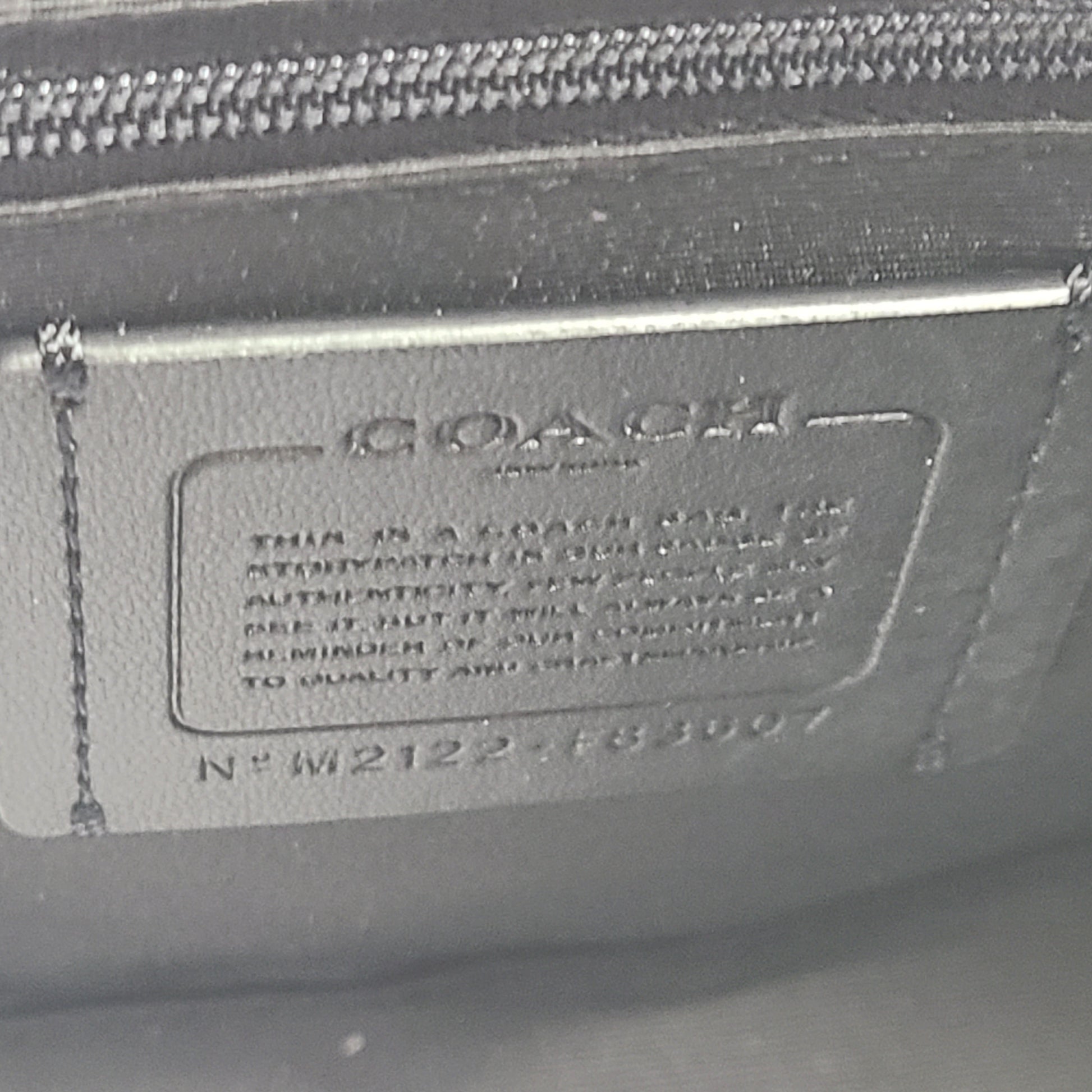 Coach brown signature-print handbag with black accents, including an interior label with the model number.