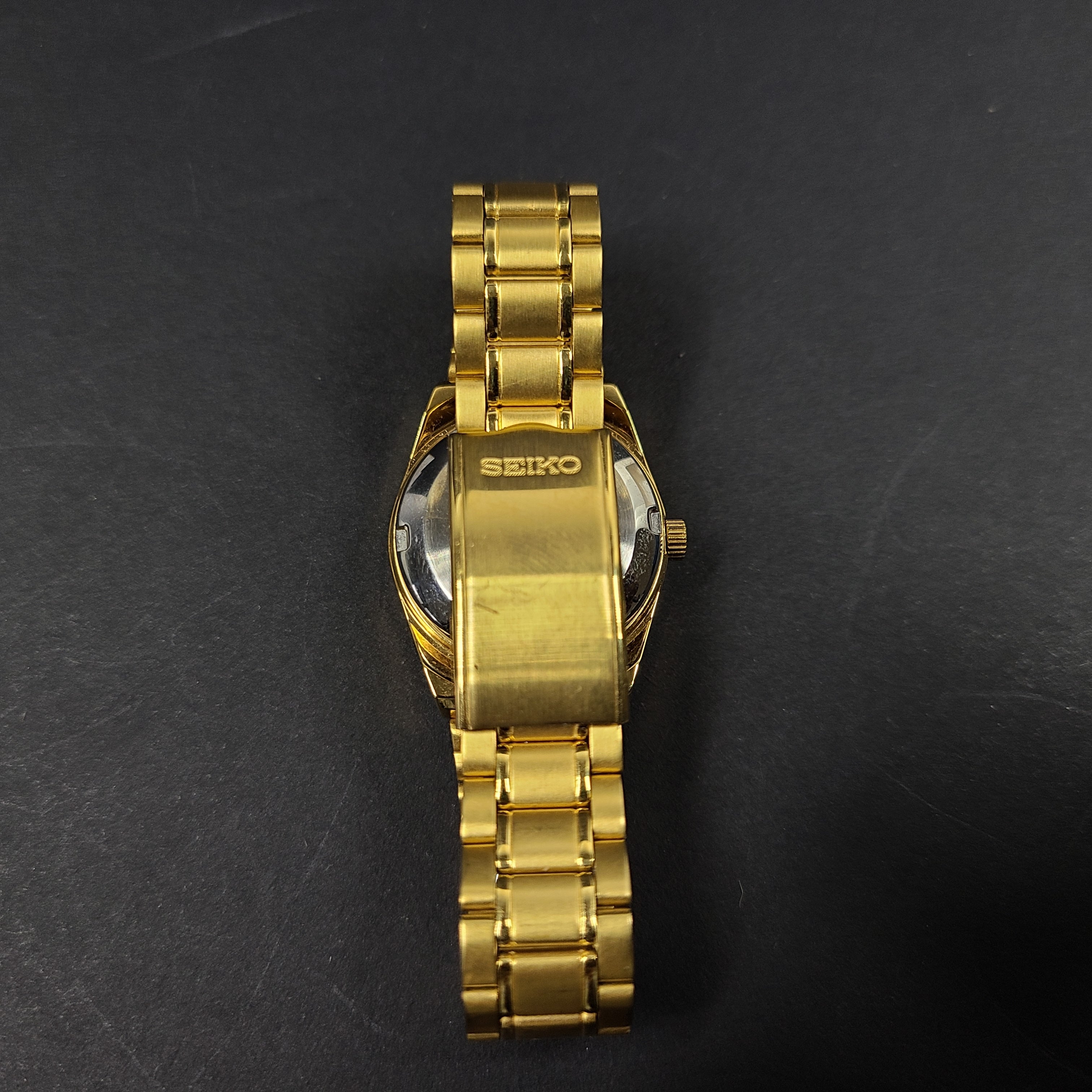 Gold-tone Seiko 5 automatic ladies watch with a black dial and stainless steel bracelet.