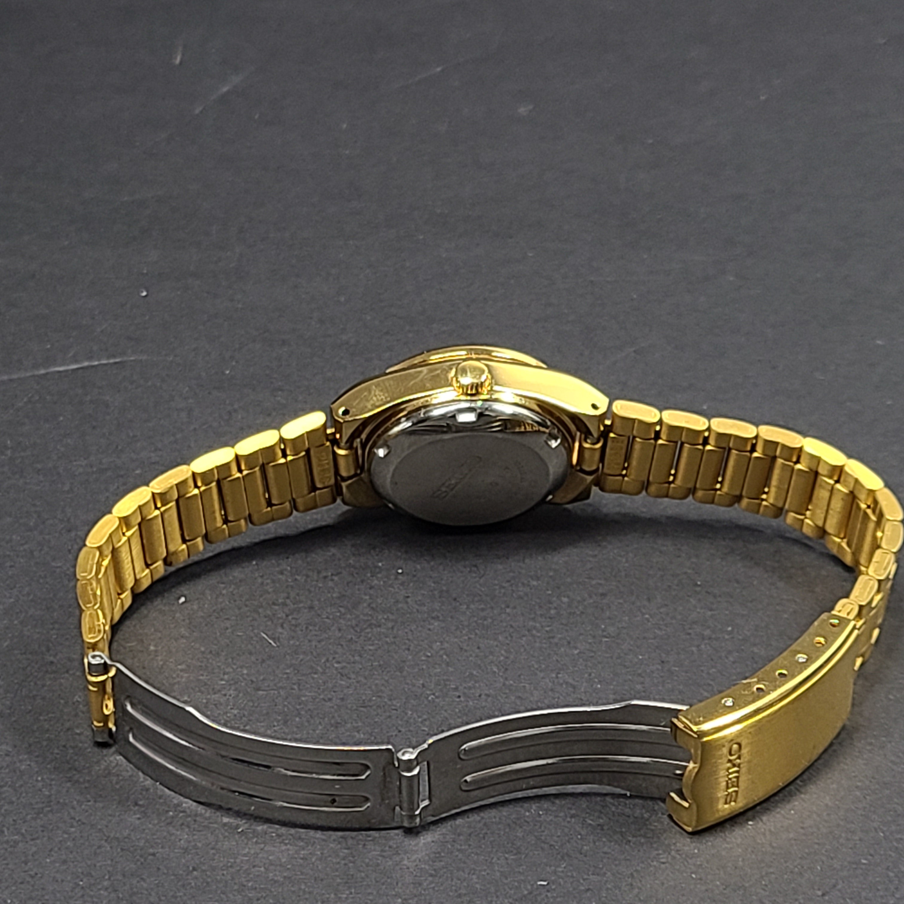 Gold-tone Seiko 5 automatic ladies watch with a black dial and stainless steel bracelet.