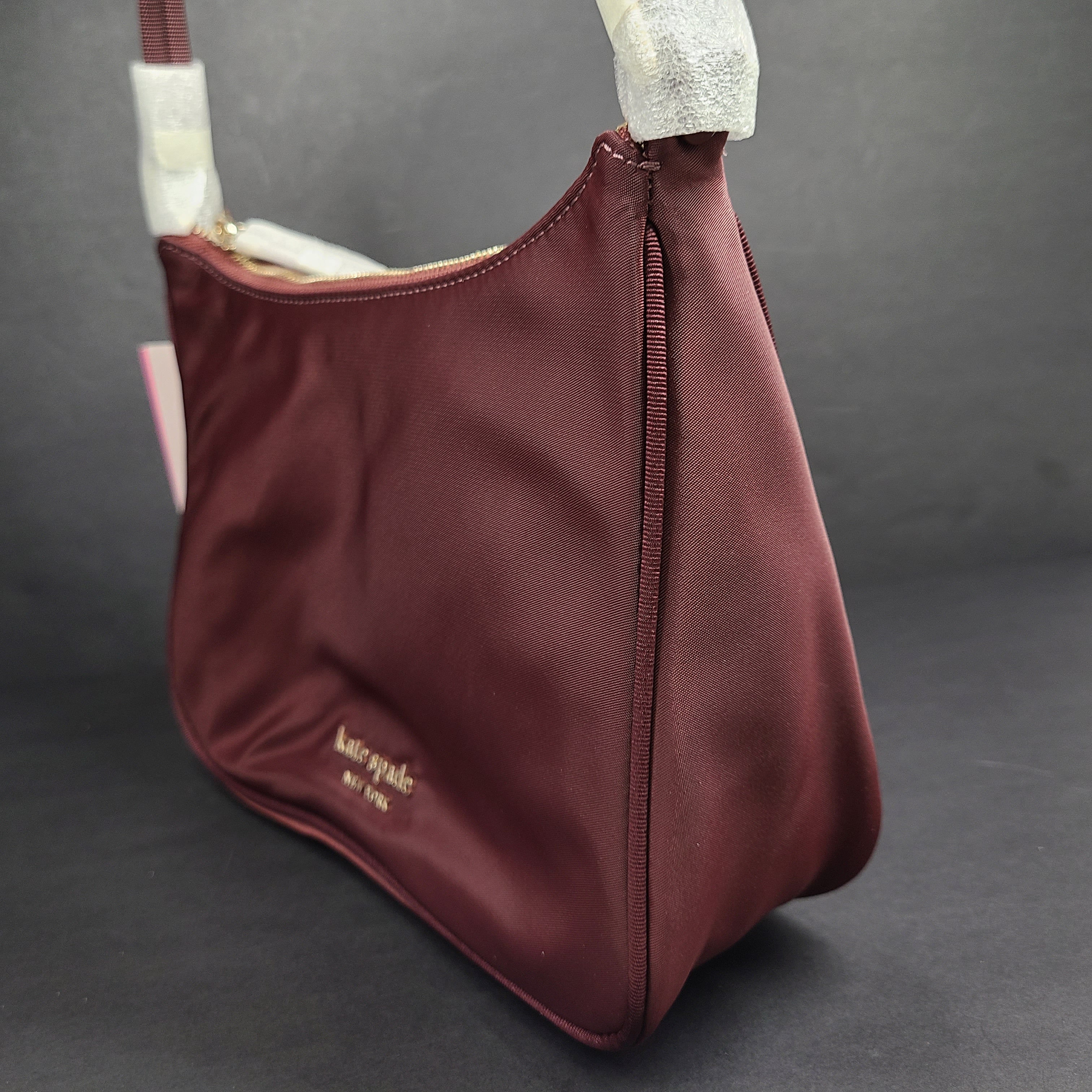 Kate Spade Sam shoulder bag in dark merlot with a refined silhouette and adjustable strap.