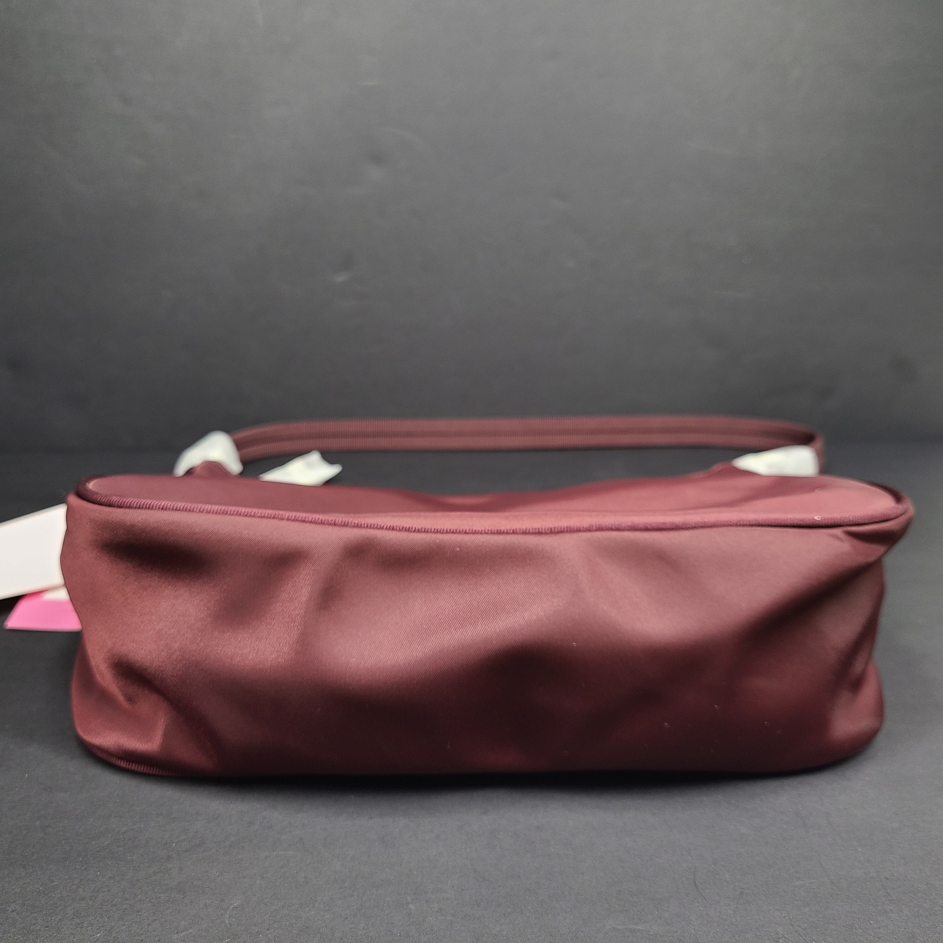 Kate Spade Sam shoulder bag in dark merlot with a refined silhouette and adjustable strap.