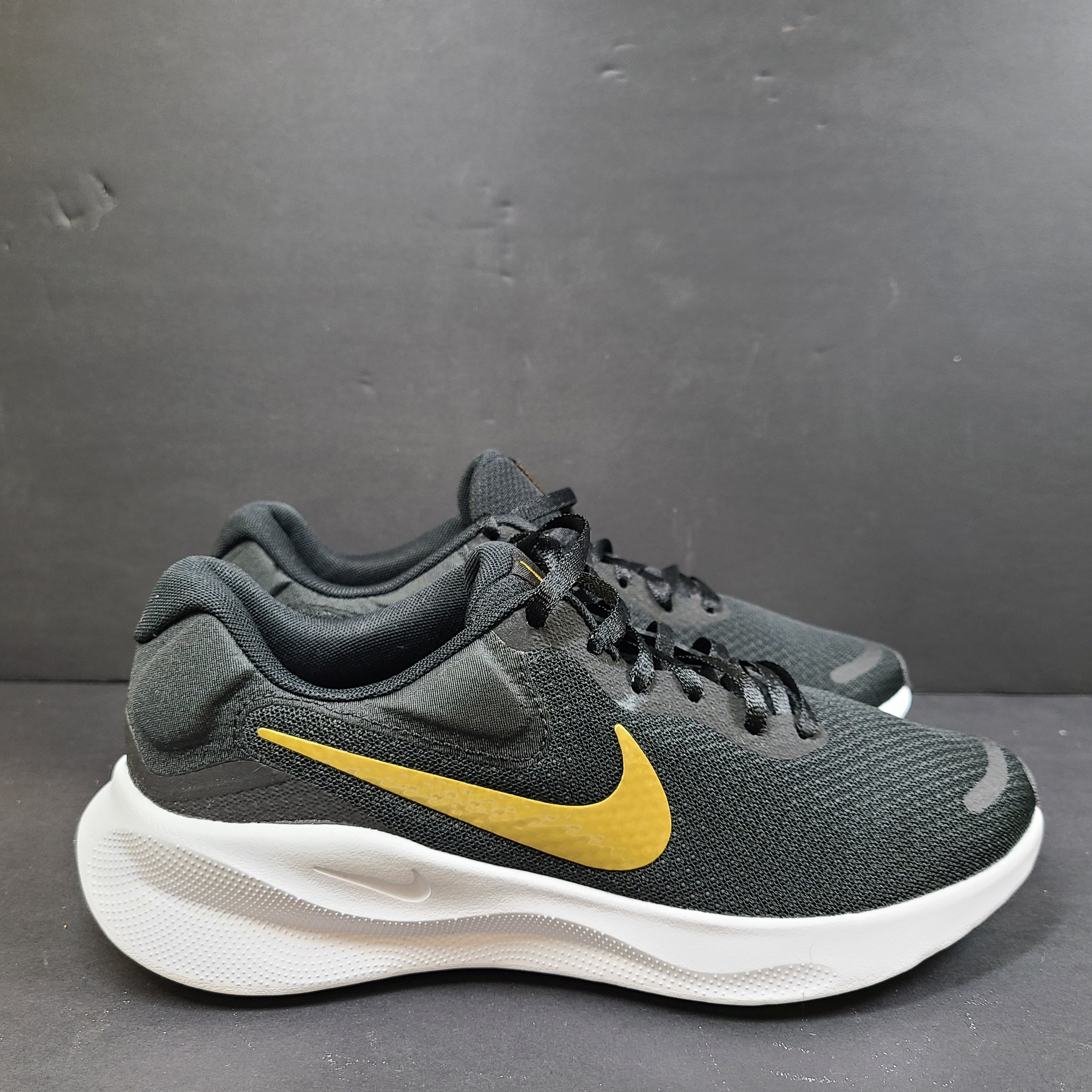 Nike Revolution 7 low-top road running shoes in black, white and metallic gold for everyday performance.