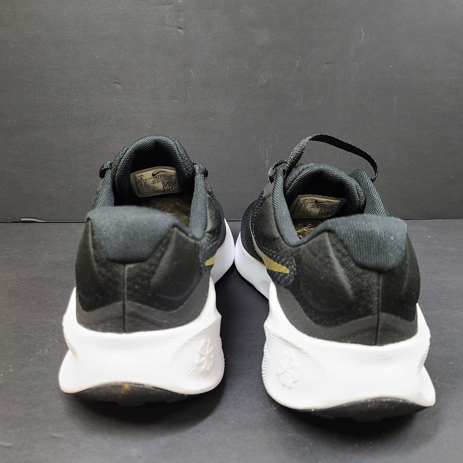 Nike Revolution 7 low-top road running shoes in black, white and metallic gold for everyday performance.