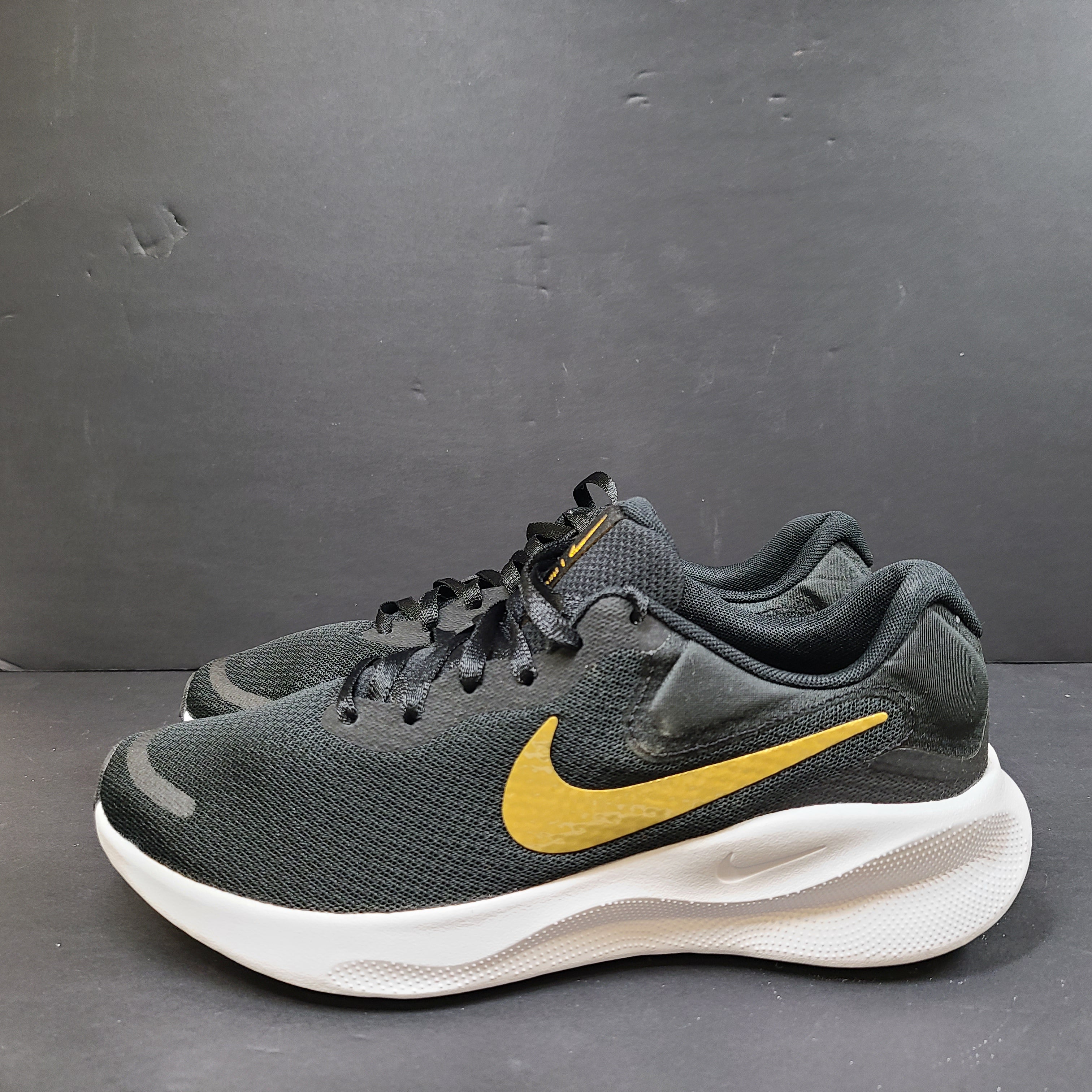 Nike Revolution 7 low-top road running shoes in black, white and metallic gold for everyday performance.
