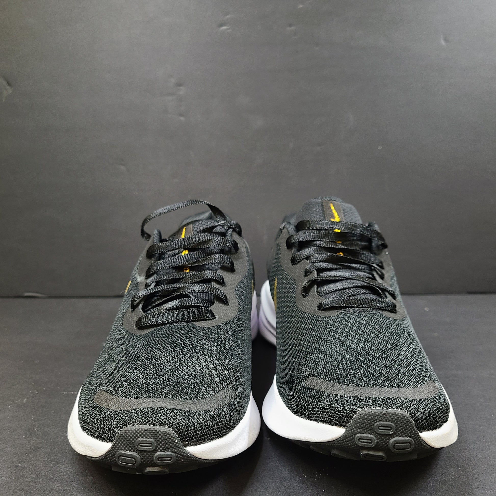 Nike Revolution 7 low-top road running shoes in black, white and metallic gold for everyday performance.