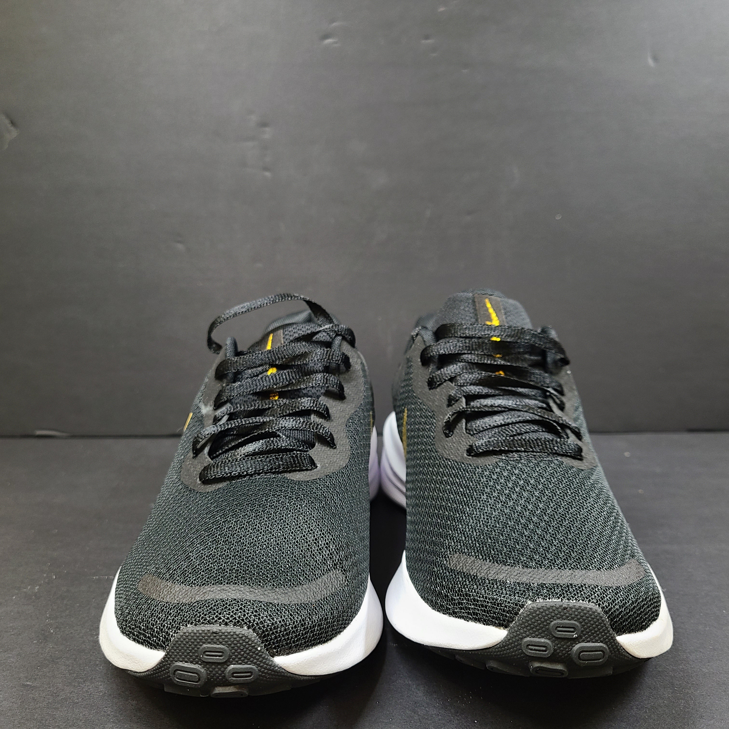 Nike Revolution 7 low-top road running shoes in black, white and metallic gold for everyday performance.