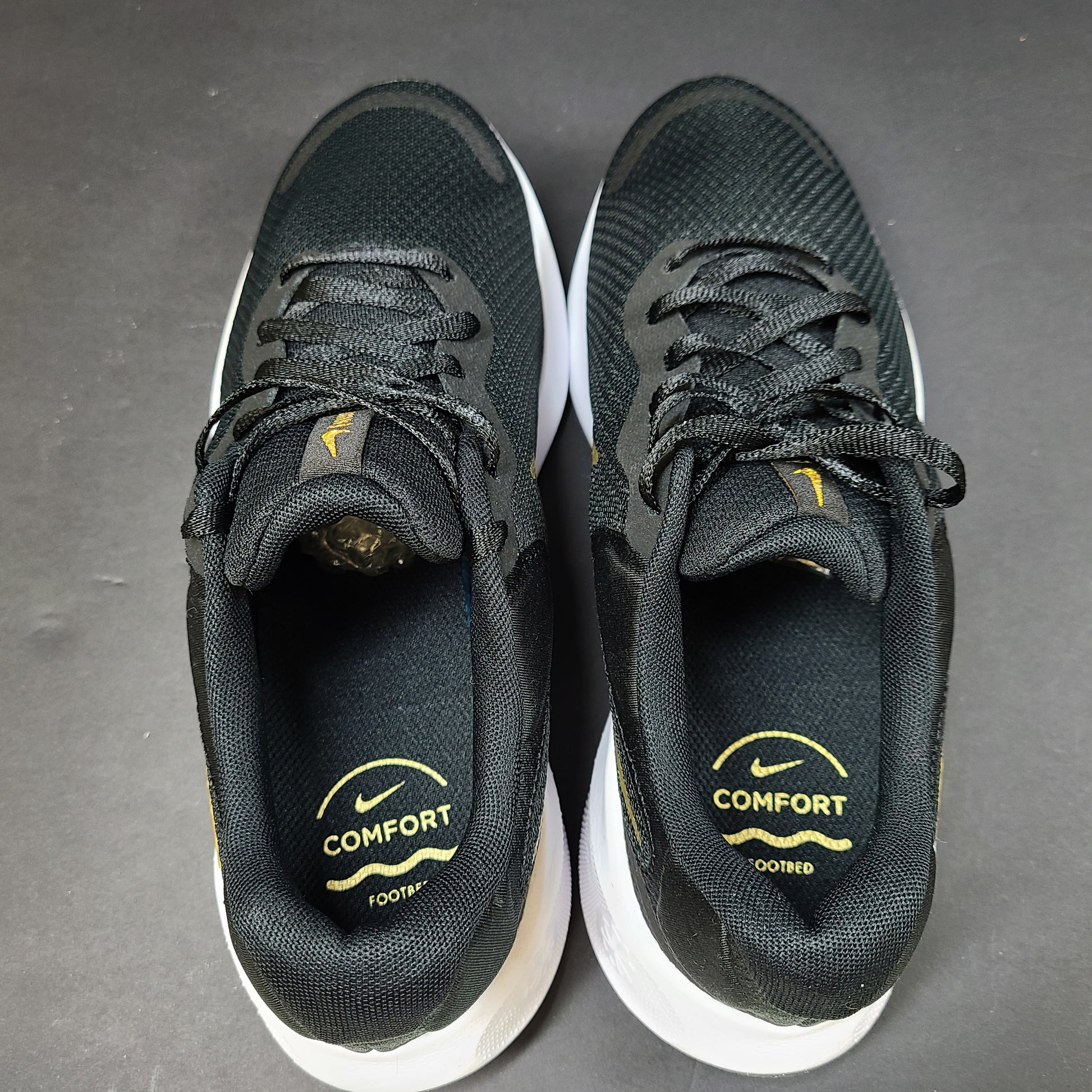 Nike Revolution 7 low-top road running shoes in black, white and metallic gold for everyday performance.