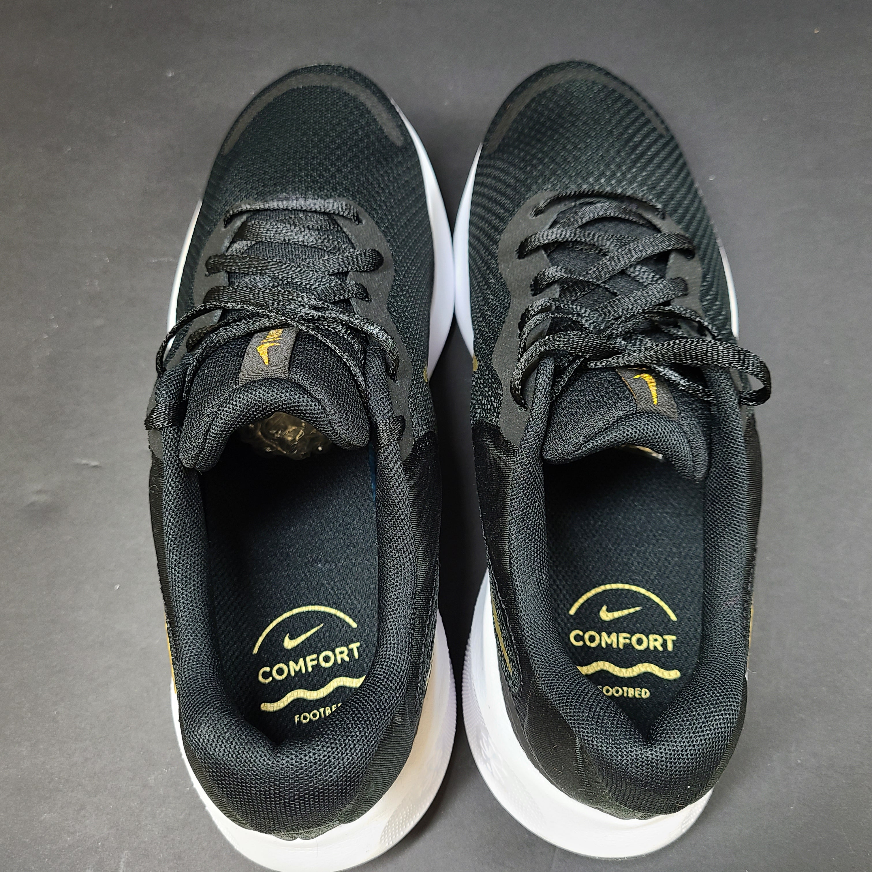 Nike Revolution 7 low-top road running shoes in black, white and metallic gold for everyday performance.