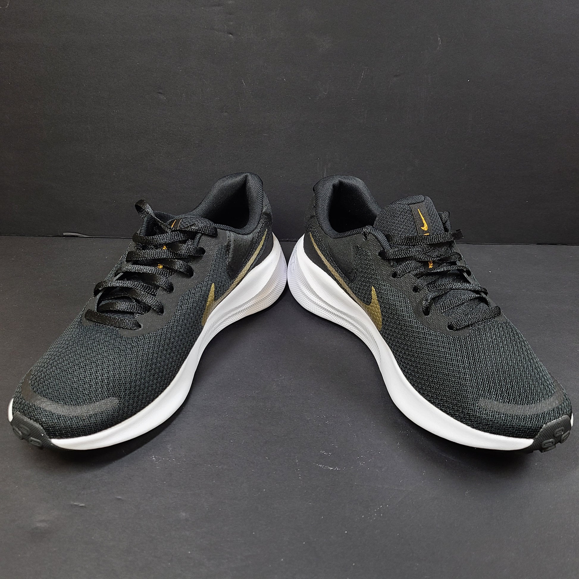 Nike Revolution 7 low-top road running shoes in black, white and metallic gold for everyday performance.