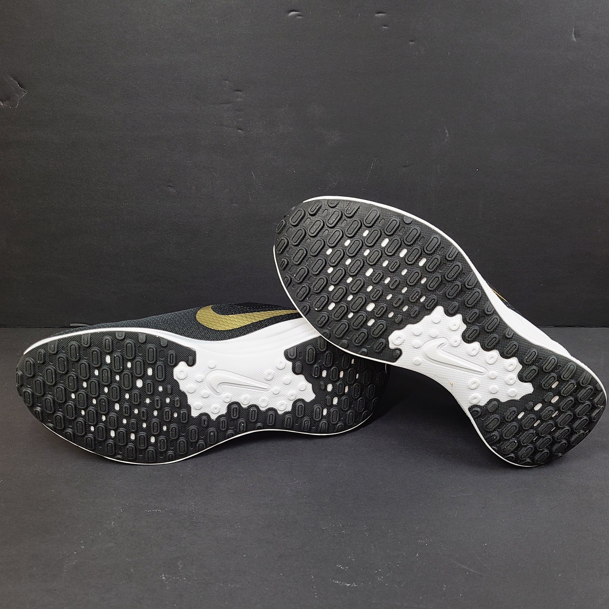 Nike Revolution 7 low-top road running shoes in black, white and metallic gold for everyday performance.