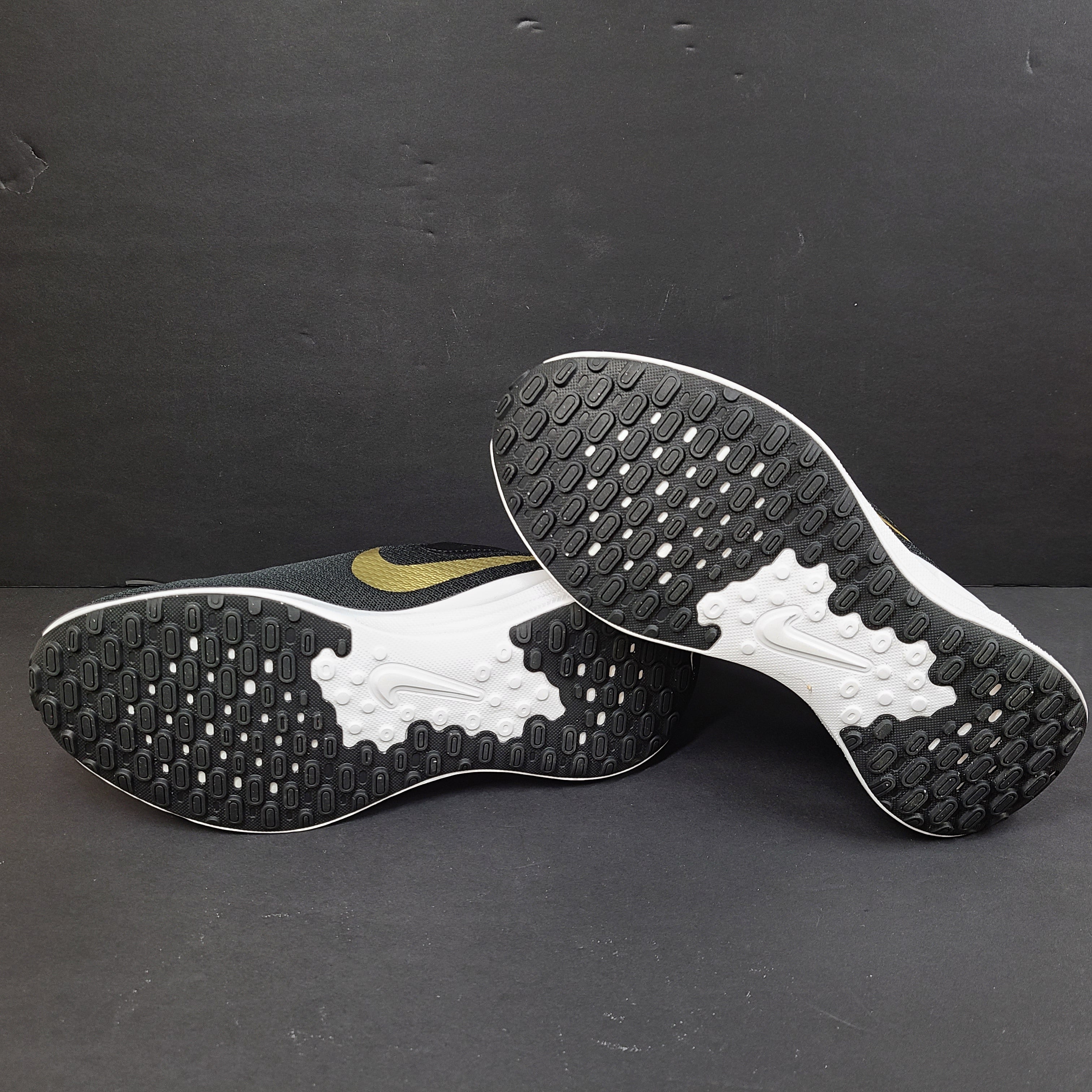 Nike Revolution 7 low-top road running shoes in black, white and metallic gold for everyday performance.