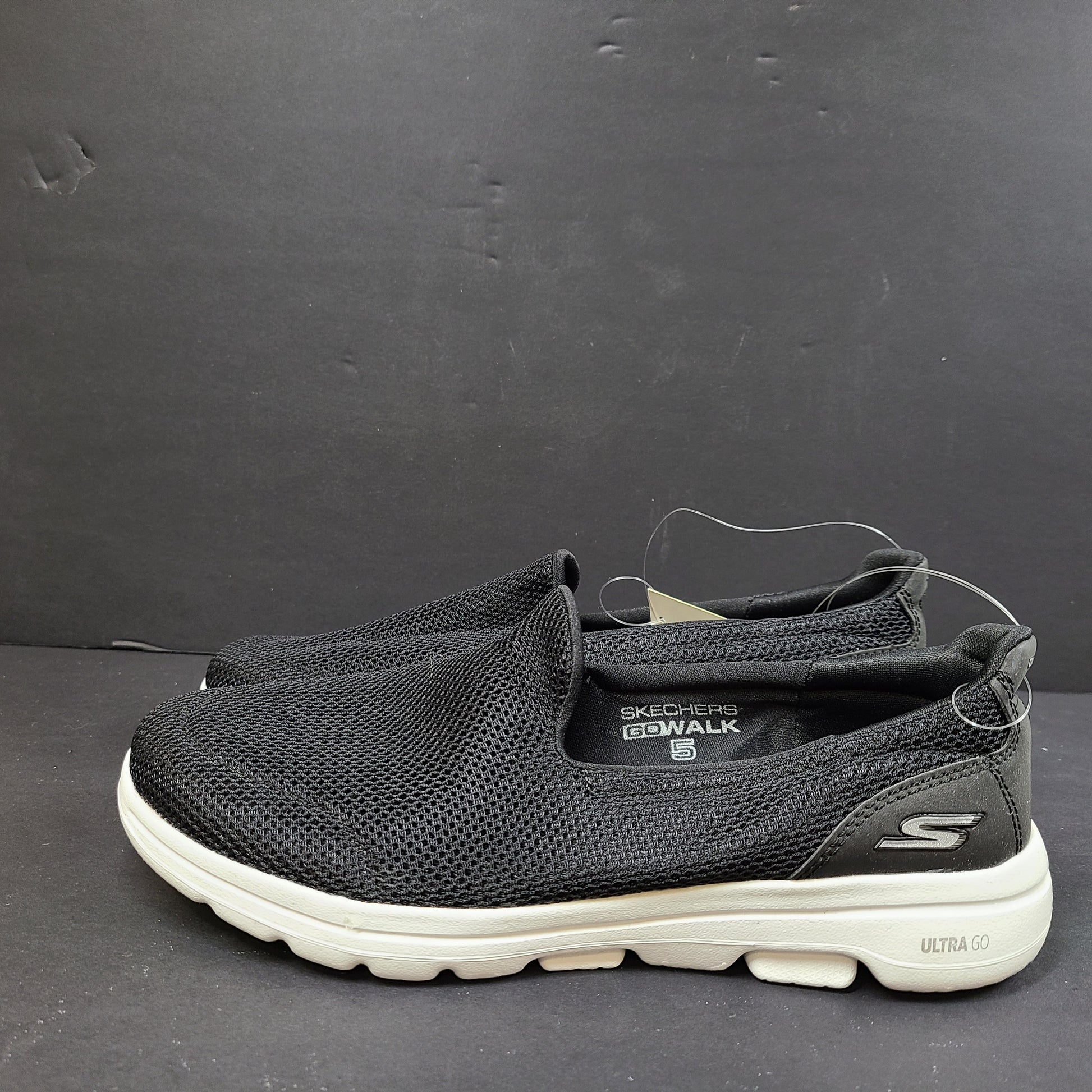 Black and white Skechers Go Walk 5 slip-on shoes with responsive cushioning and Quick-Fit heel for easy on and off.