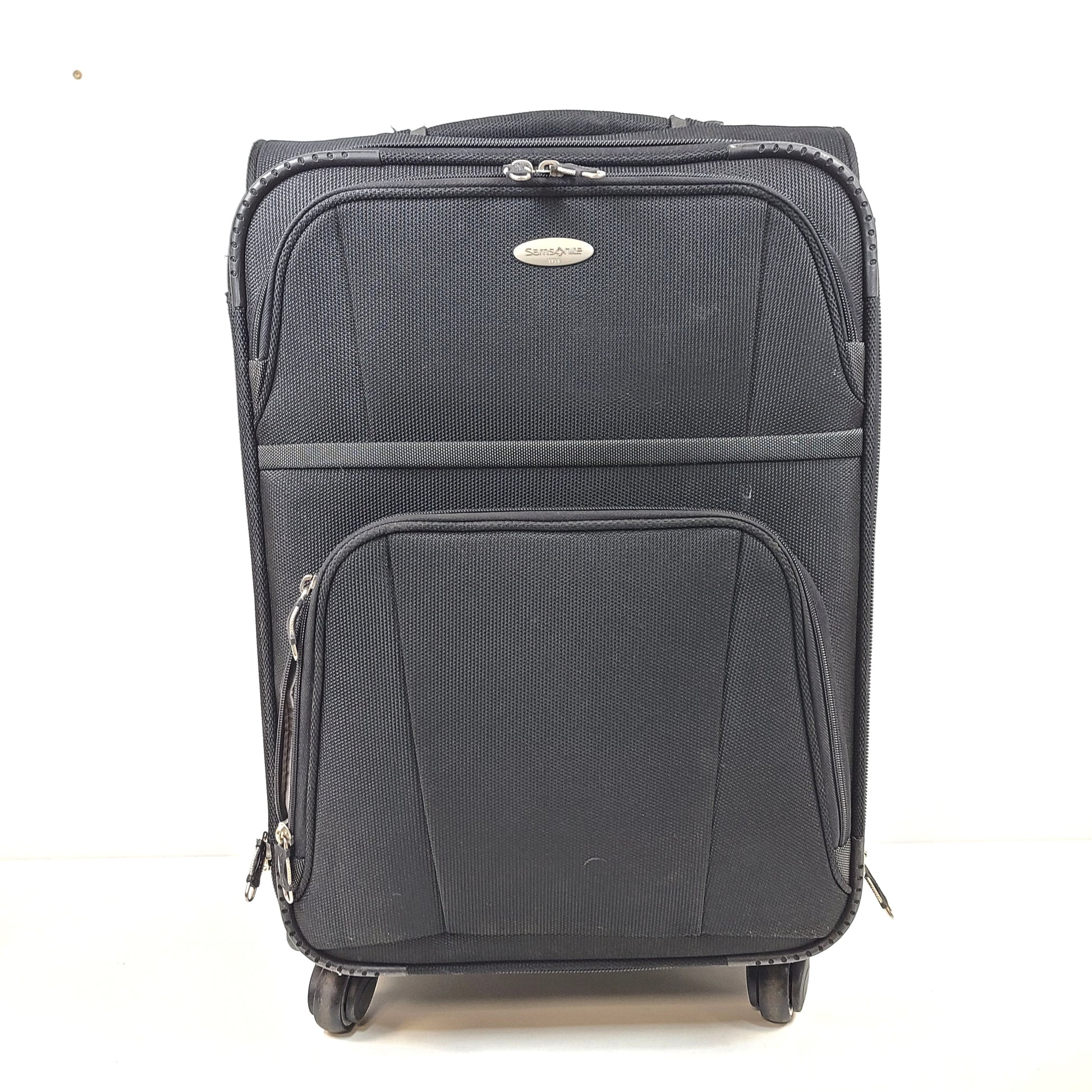 Black Samsonite suitcase QC-002454 with minor scuff marks and labeled material composition.