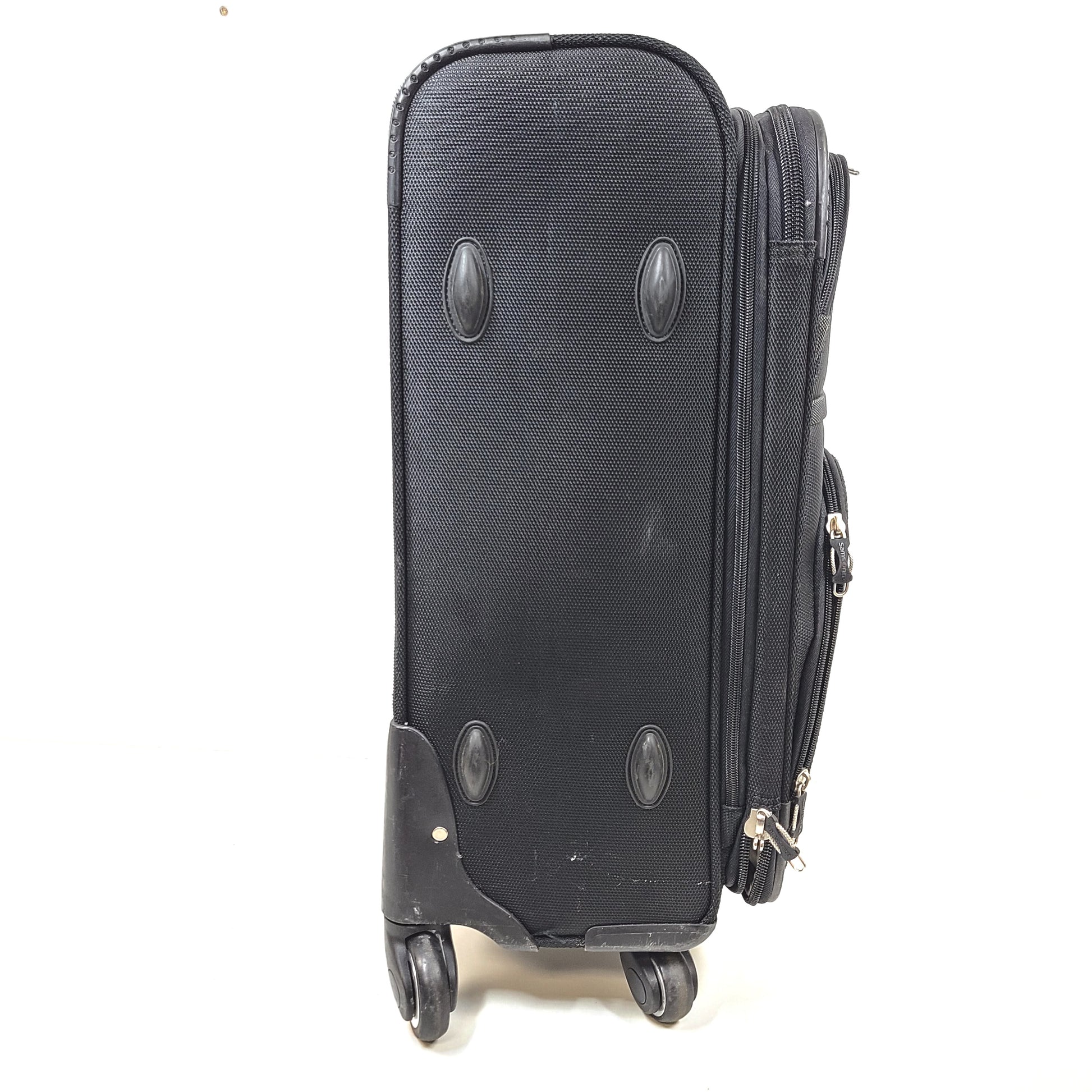 Black Samsonite suitcase QC-002454 with minor scuff marks and labeled material composition.