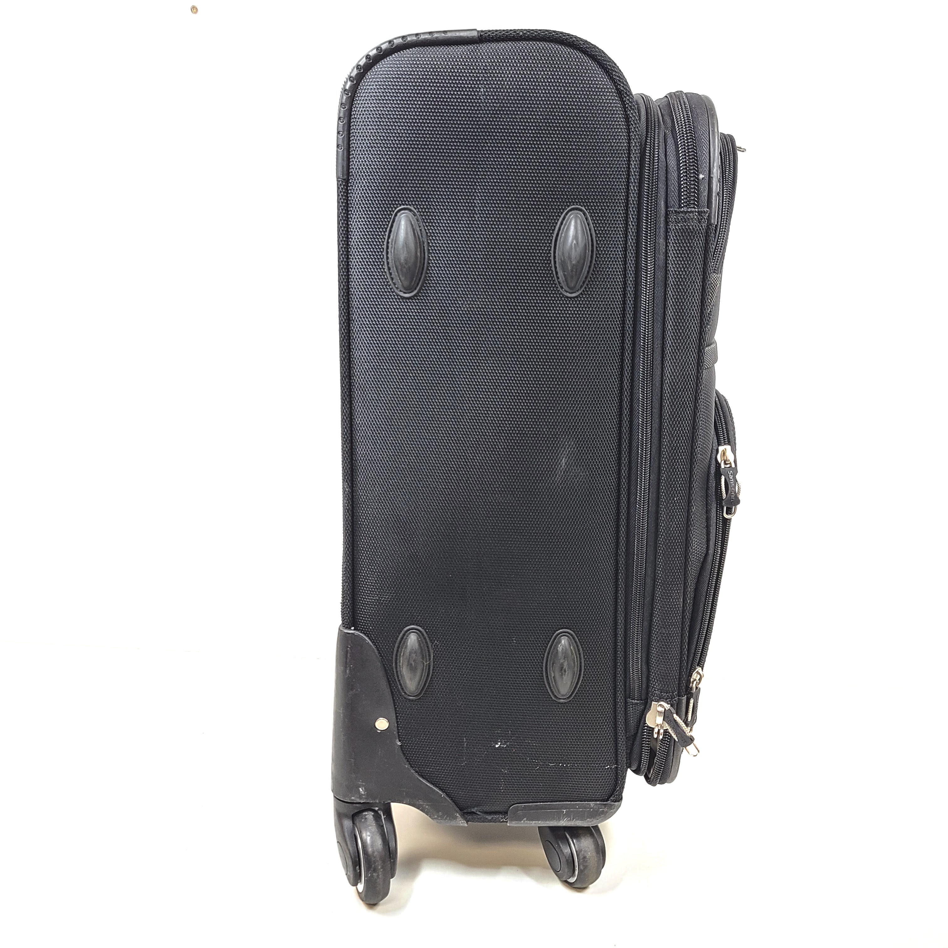 Black Samsonite suitcase QC-002454 with minor scuff marks and labeled material composition.