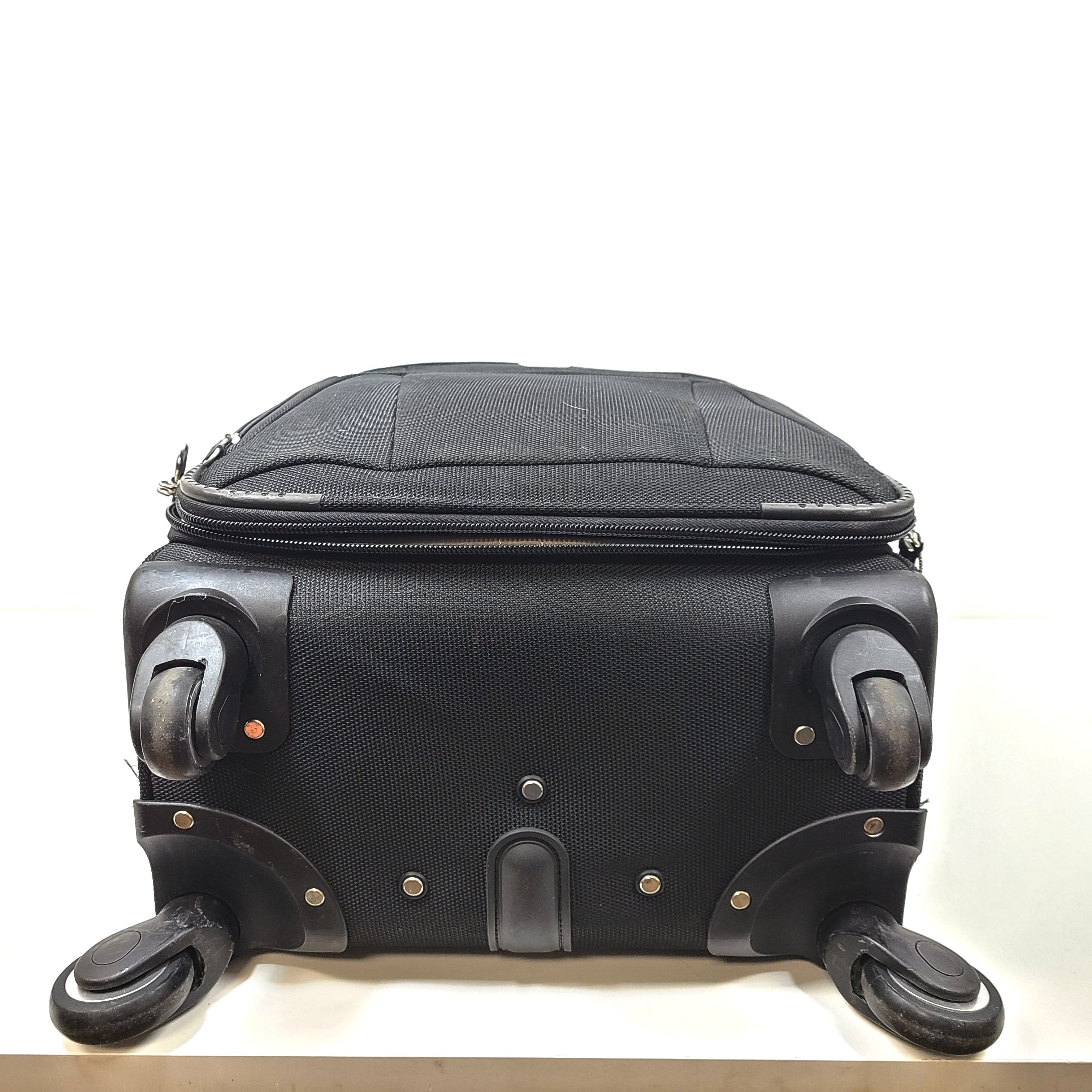 Black Samsonite suitcase QC-002454 with minor scuff marks and labeled material composition.