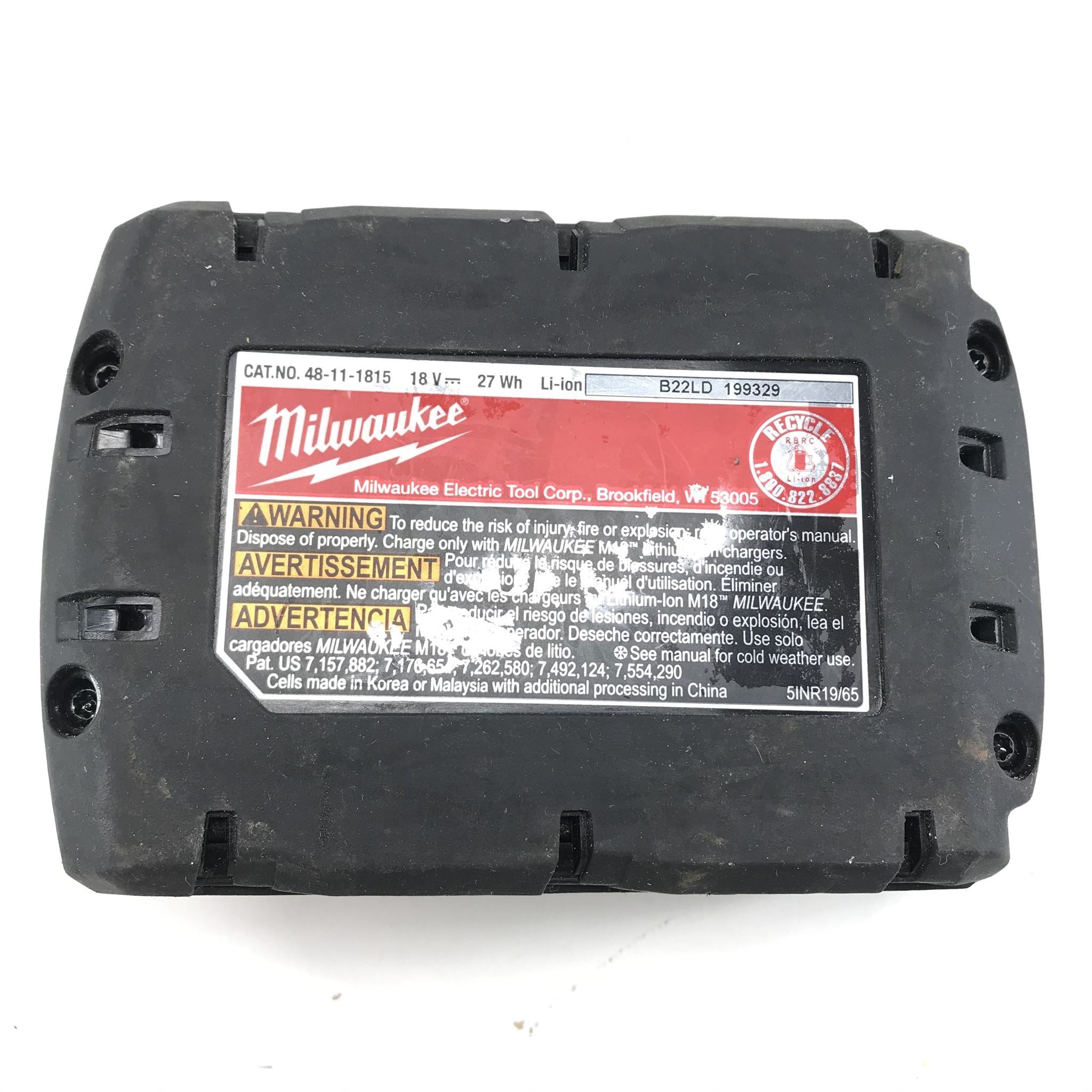 Back view of a Milwaukee battery pack with warning label on a white background