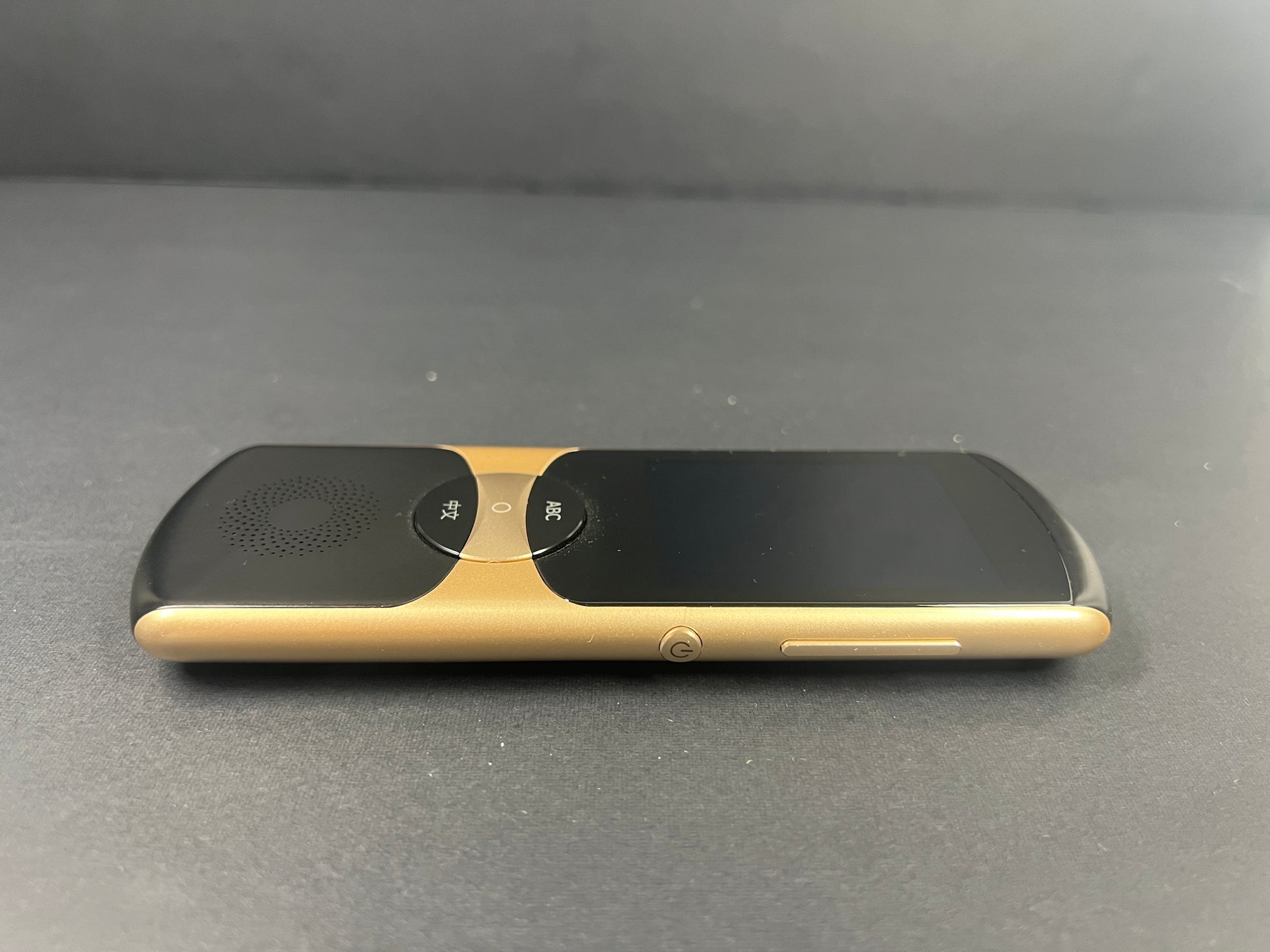 Black and gold iFLYTEK AIT02 voice translator showing front and back with buttons and display screen visible