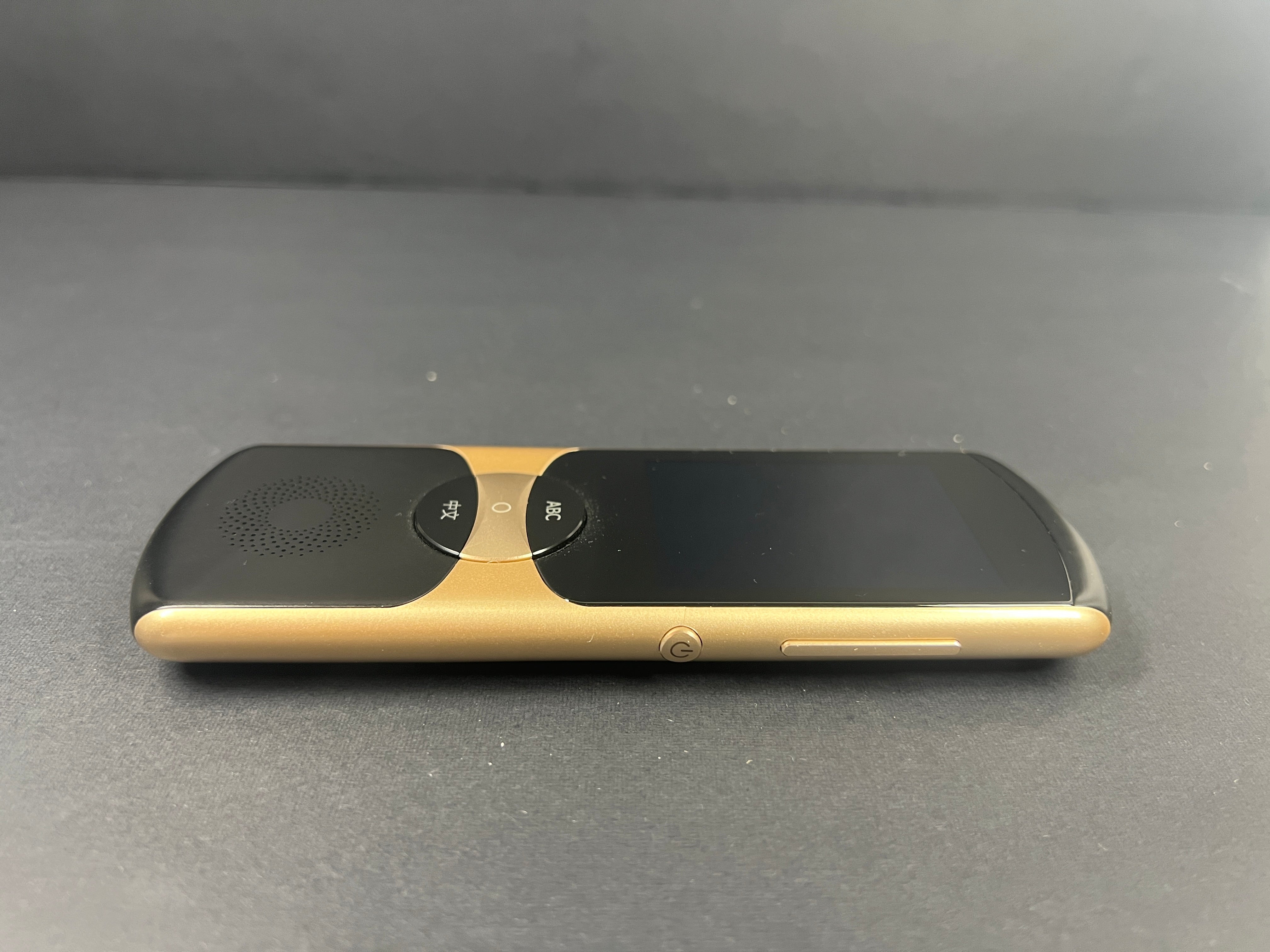 Black and gold iFLYTEK AIT02 voice translator showing front and back with buttons and display screen visible