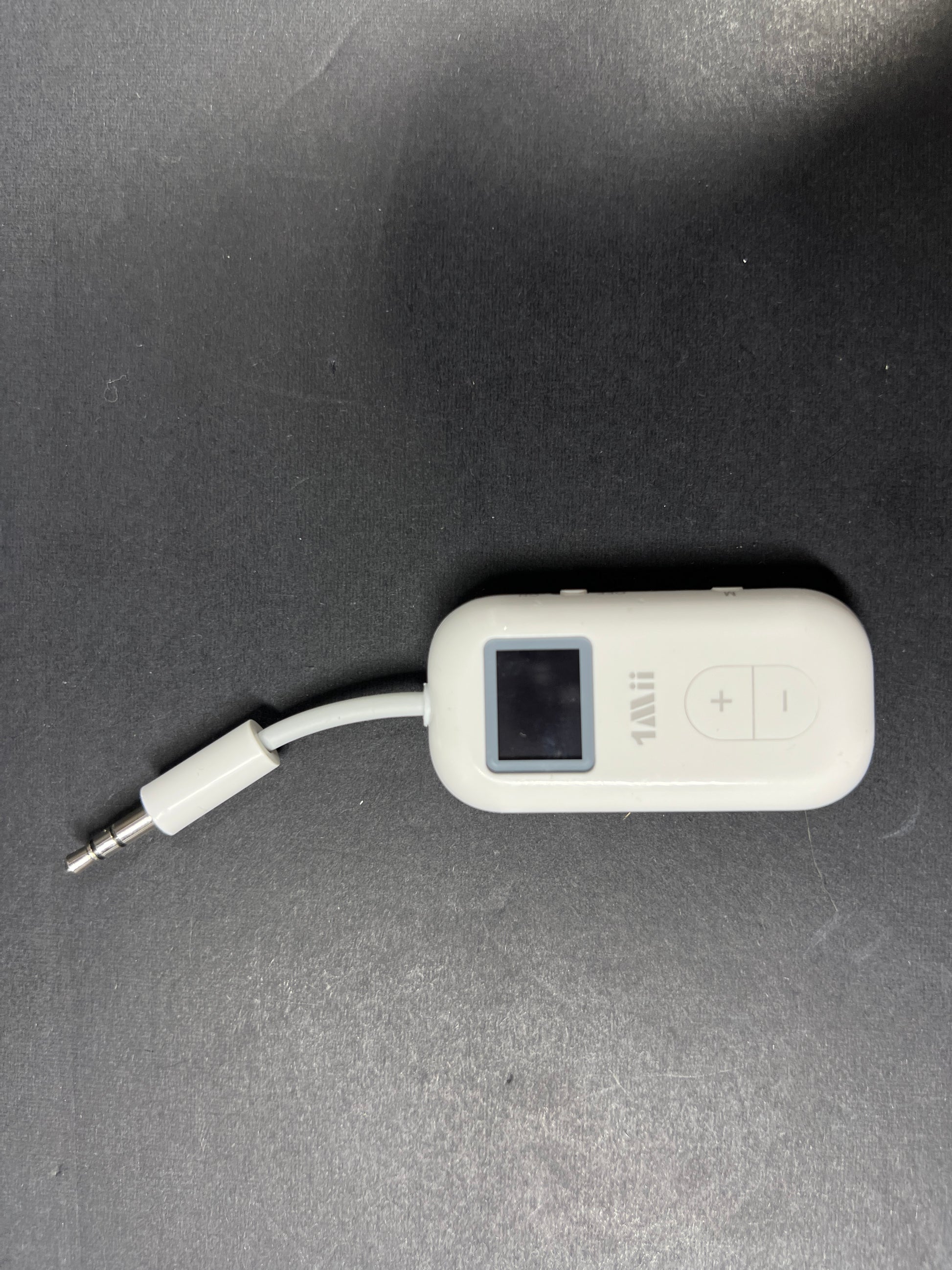 Small white Bluetooth audio adapter with display and 3.5mm jack designed for wireless headphone use on planes
