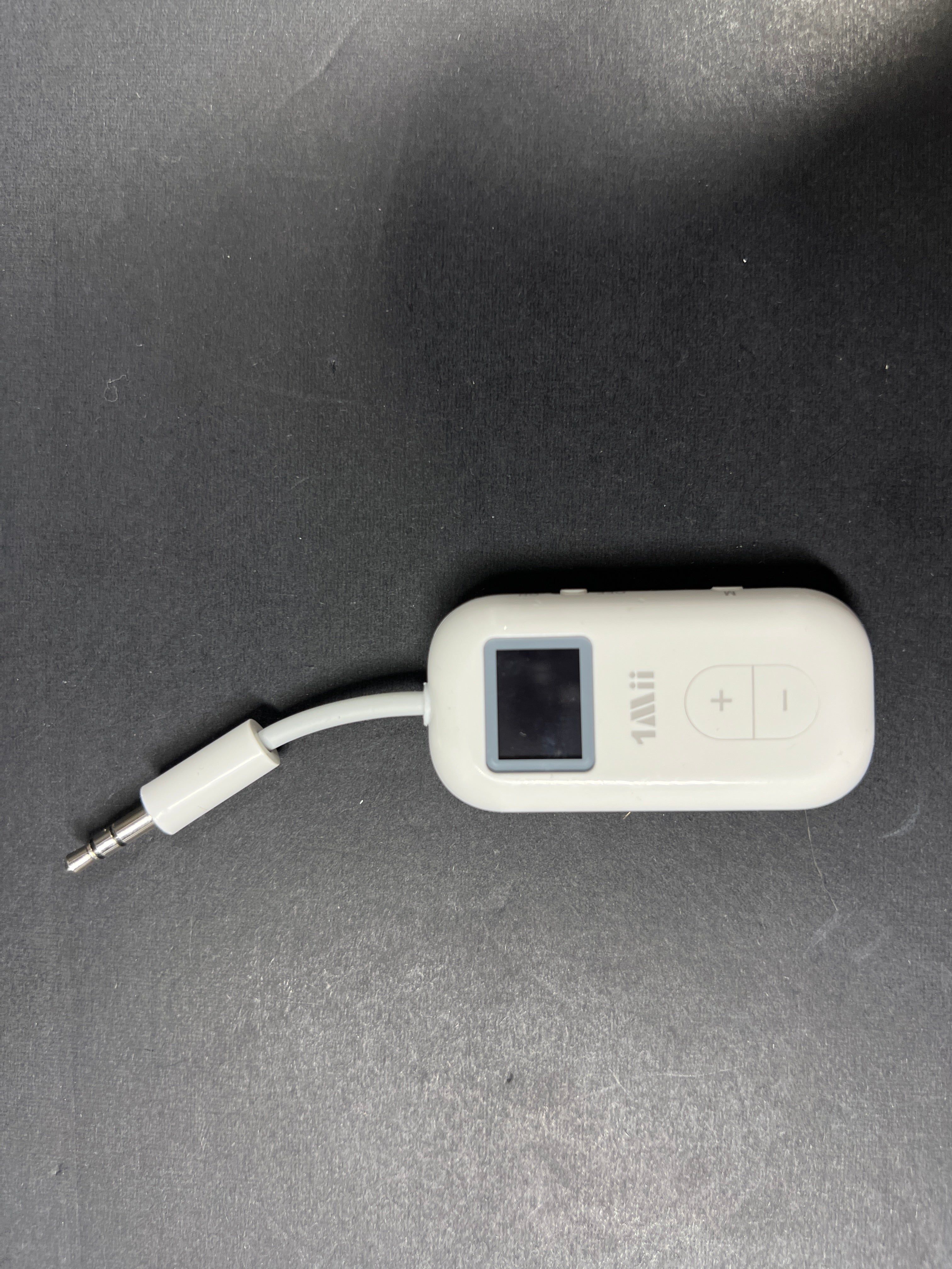 Small white Bluetooth audio adapter with display and 3.5mm jack designed for wireless headphone use on planes