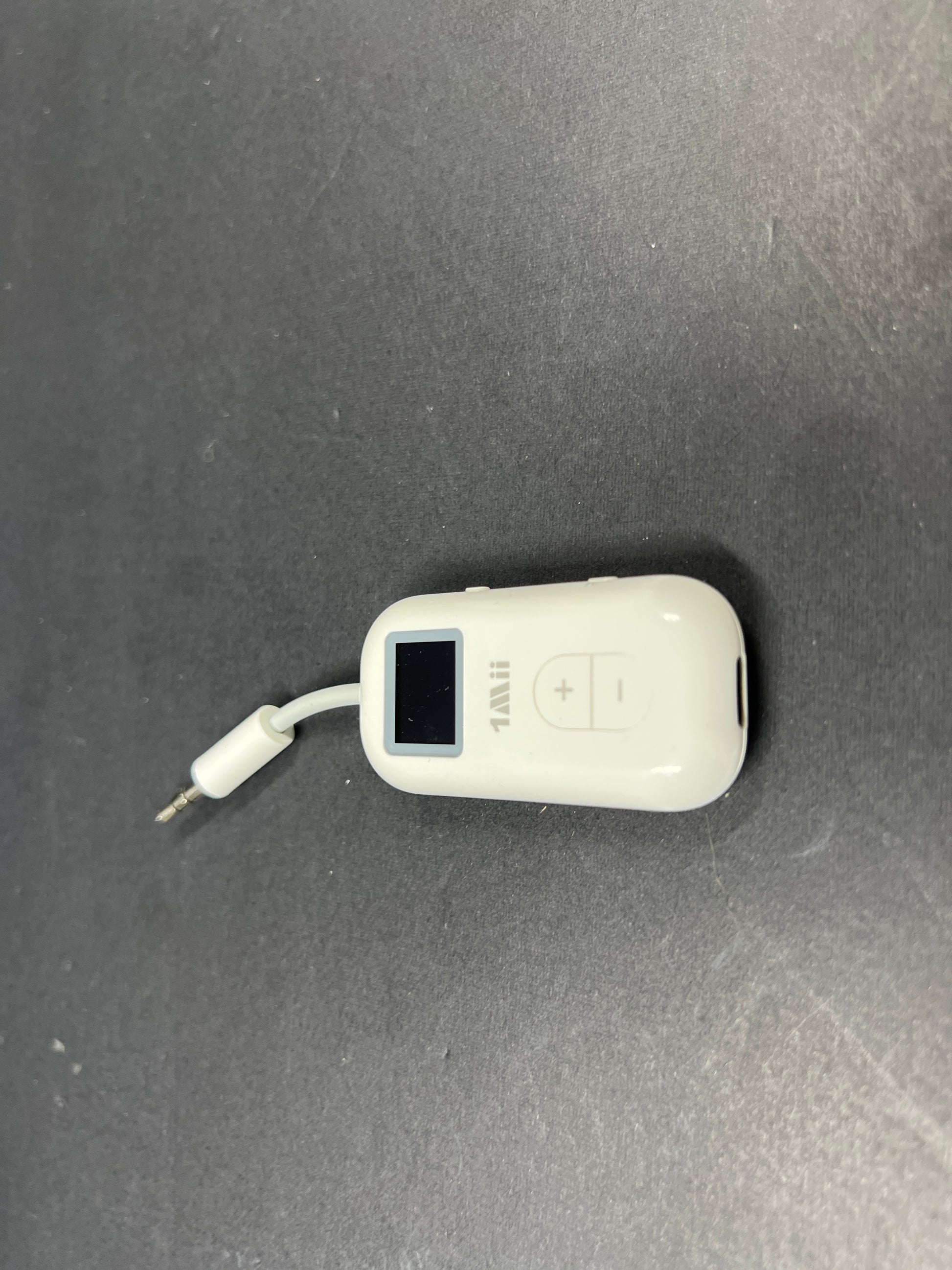 Small white Bluetooth audio adapter with display and 3.5mm jack designed for wireless headphone use on planes