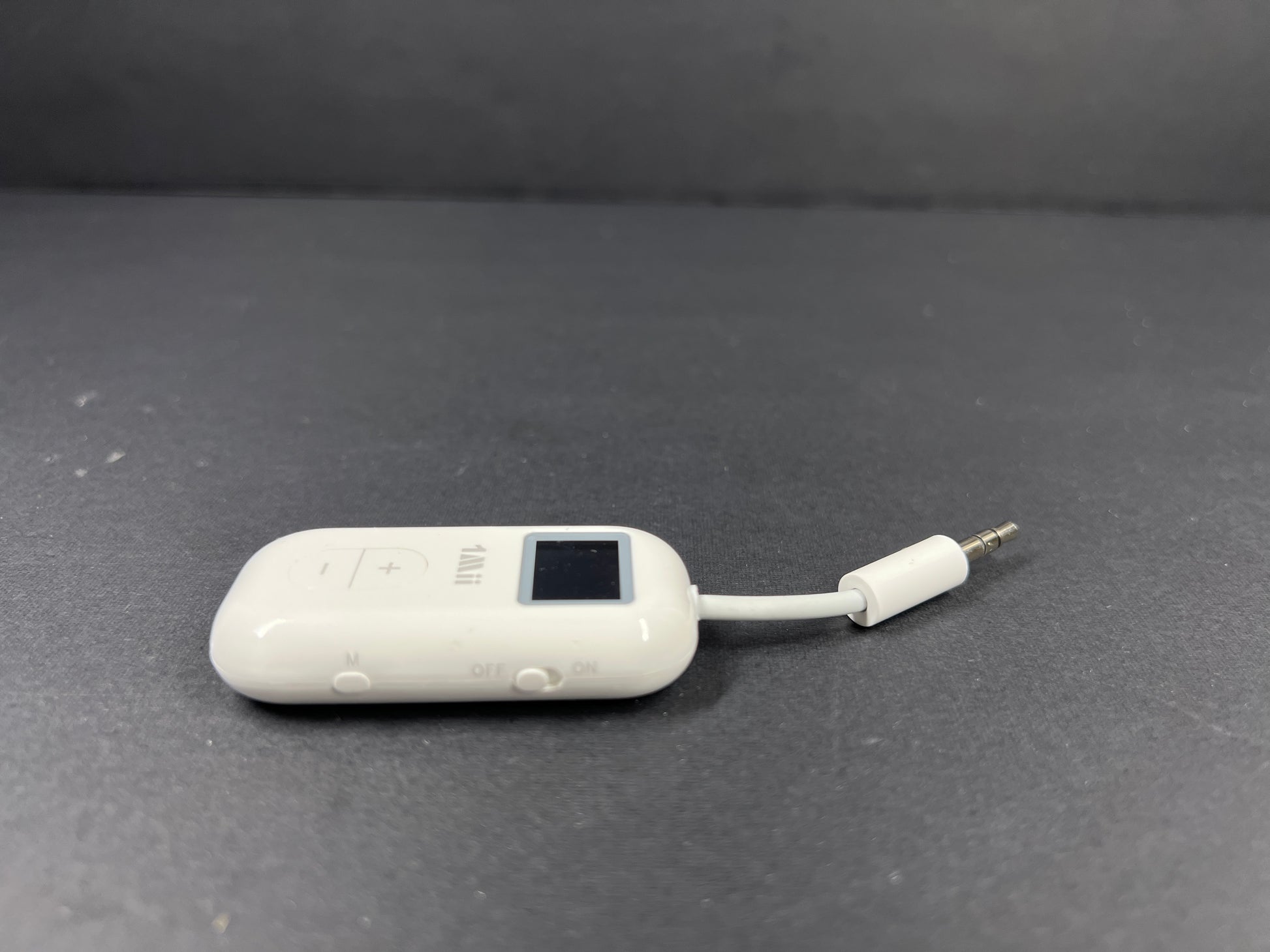 Small white Bluetooth audio adapter with display and 3.5mm jack designed for wireless headphone use on planes