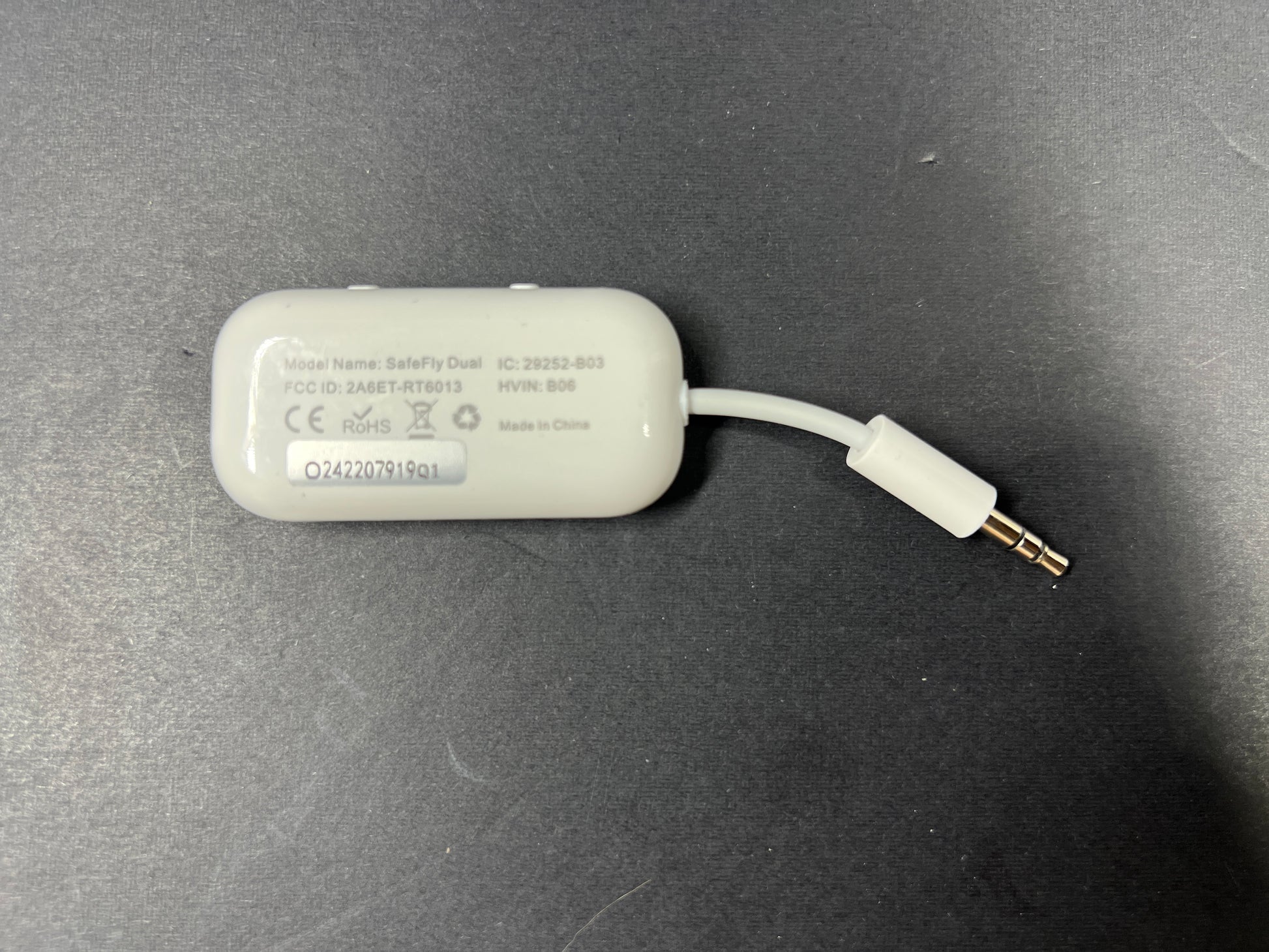 Small white Bluetooth audio adapter with display and 3.5mm jack designed for wireless headphone use on planes