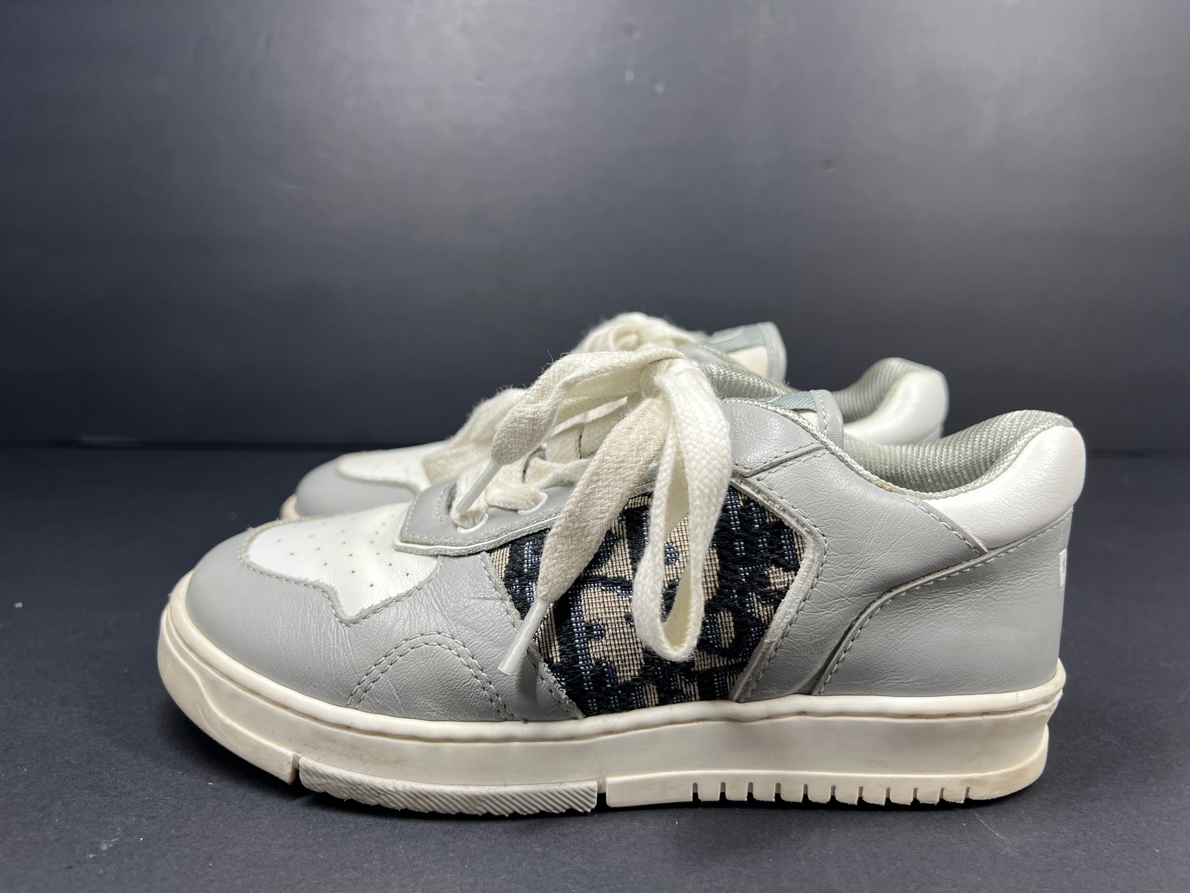 A pair of fashionable grey and white Dior women's sneakers.
