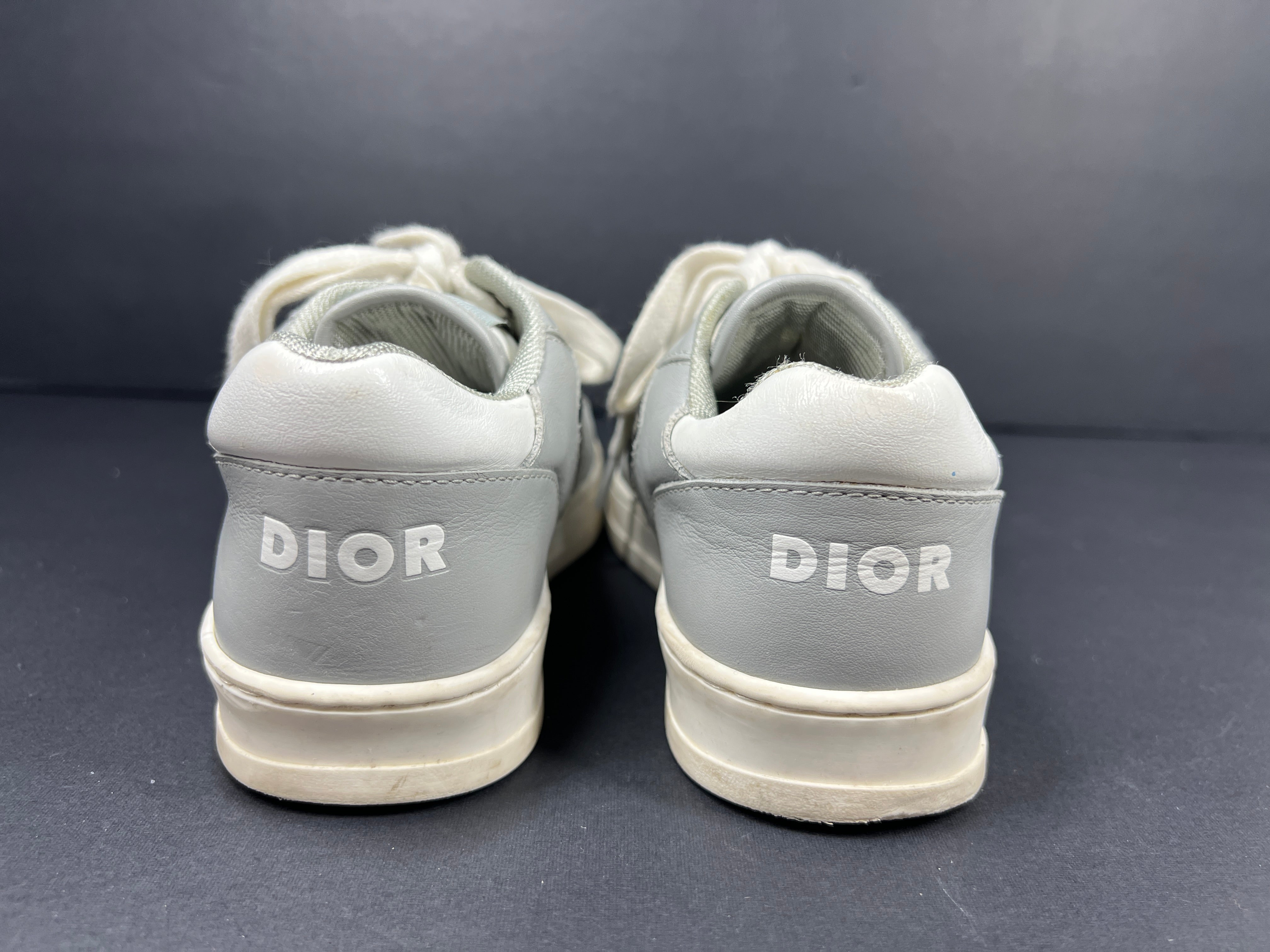 A pair of fashionable grey and white Dior women's sneakers.