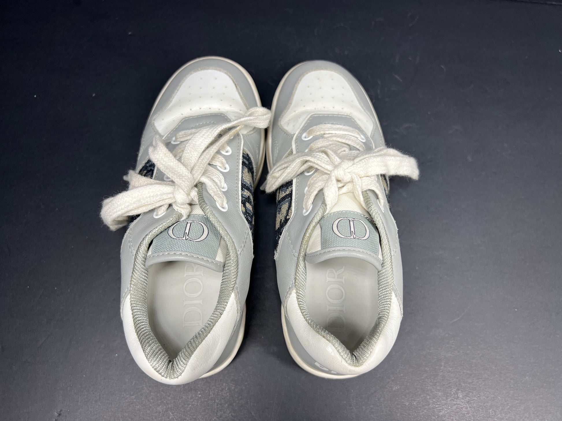A pair of fashionable grey and white Dior women's sneakers.