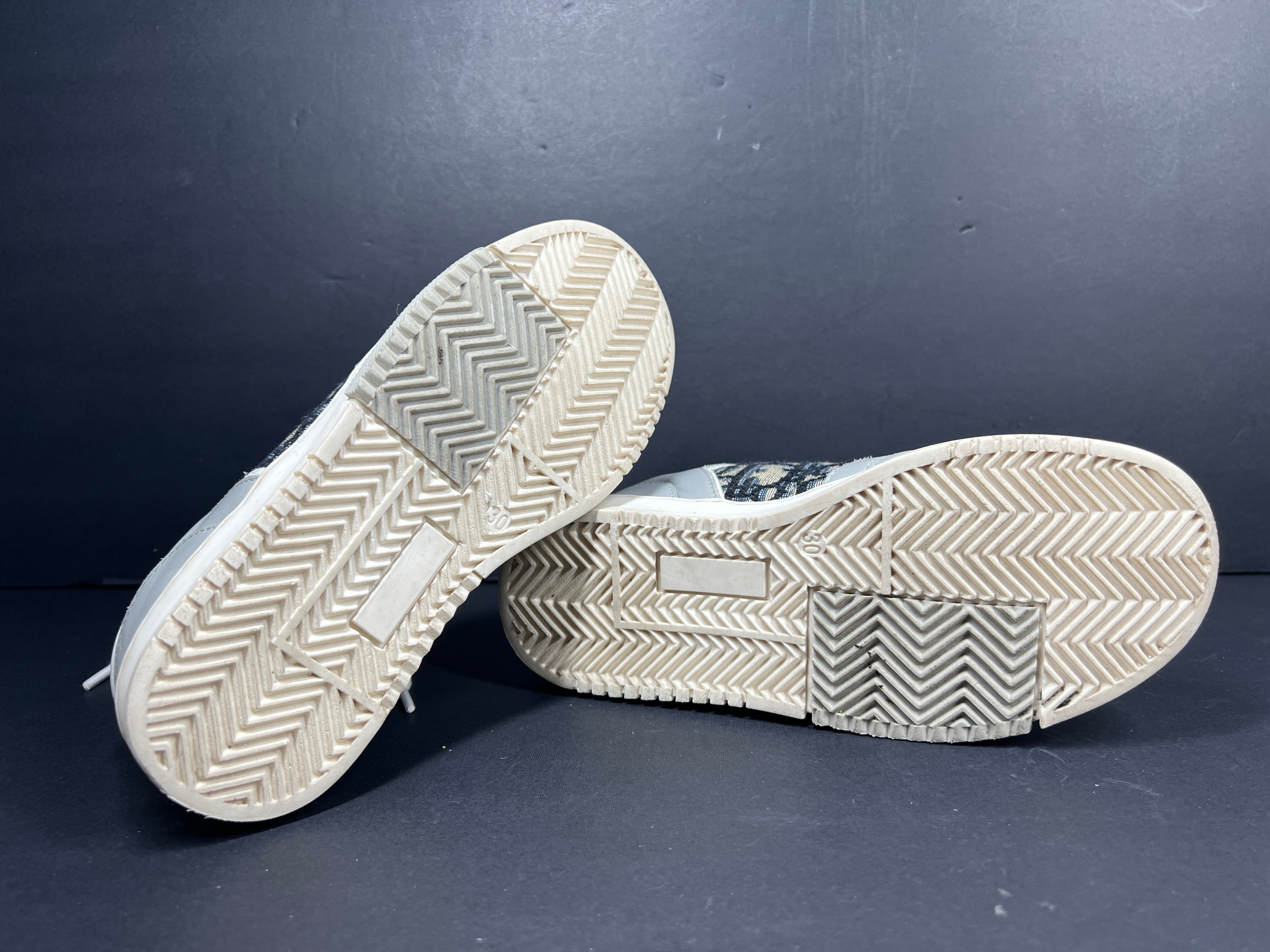 A pair of fashionable grey and white Dior women's sneakers.