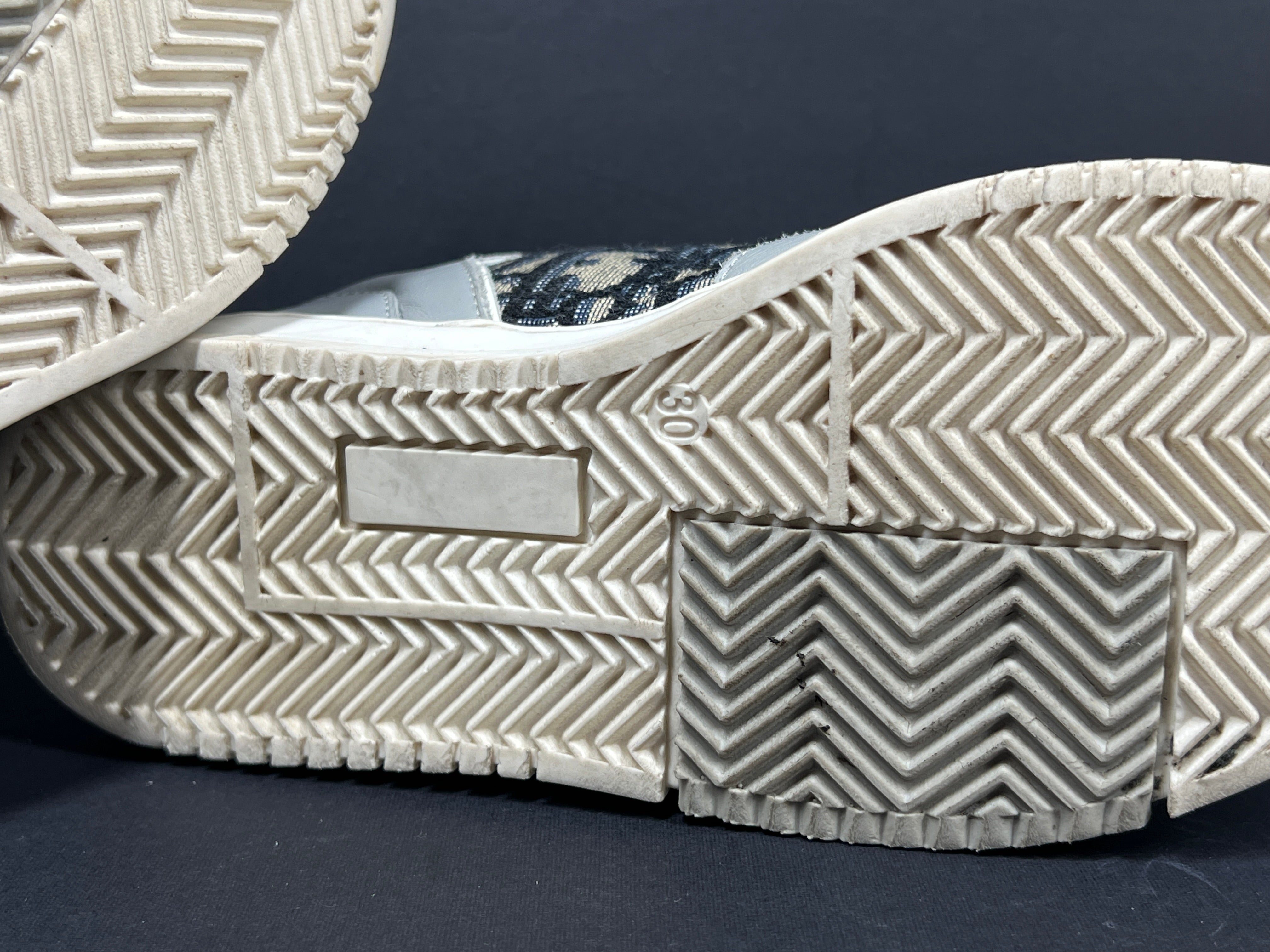 A pair of fashionable grey and white Dior women's sneakers.