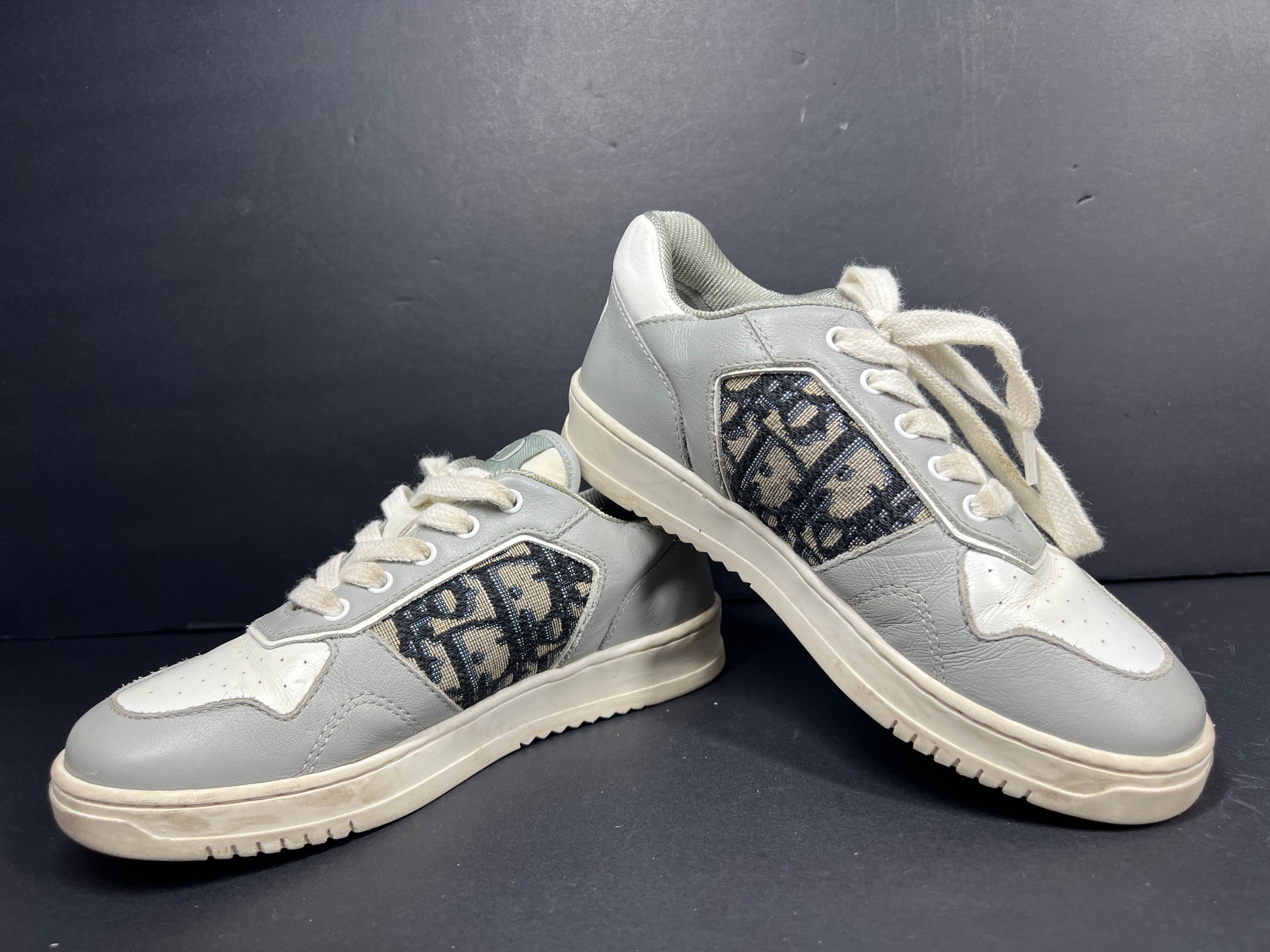 A pair of fashionable grey and white Dior women's sneakers.