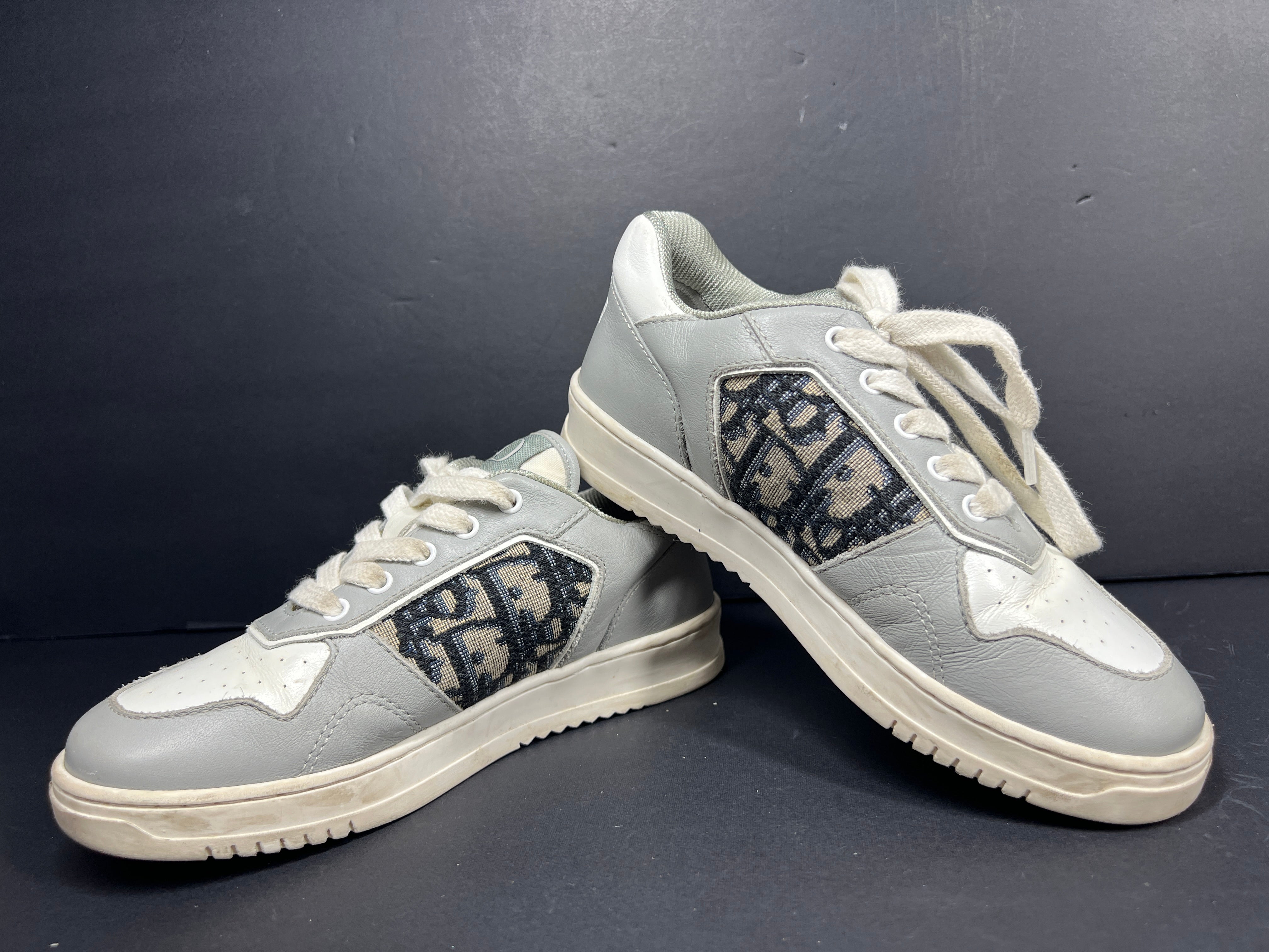A pair of fashionable grey and white Dior women's sneakers.