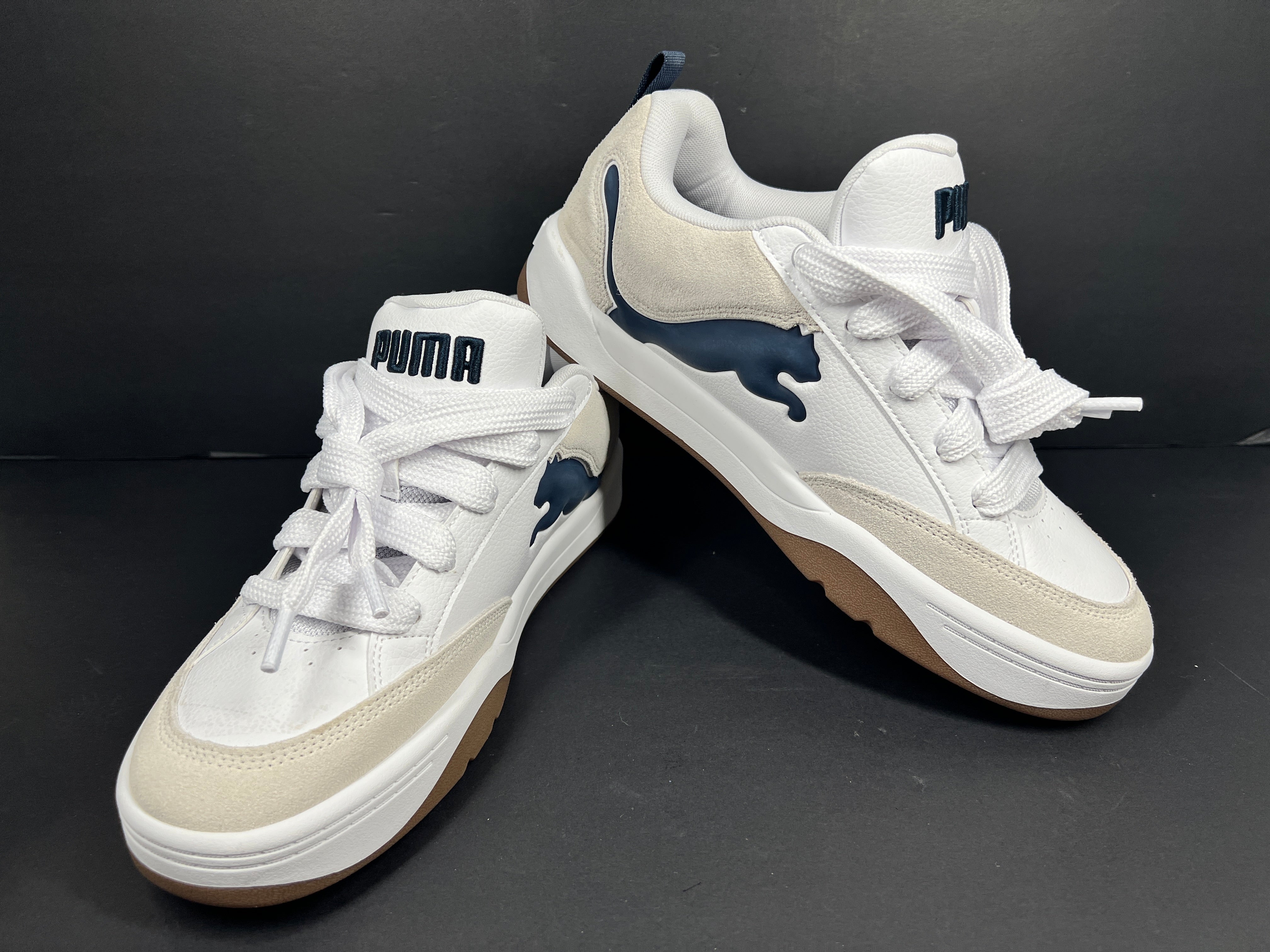 A pair of Puma sneakers in white and navy color scheme